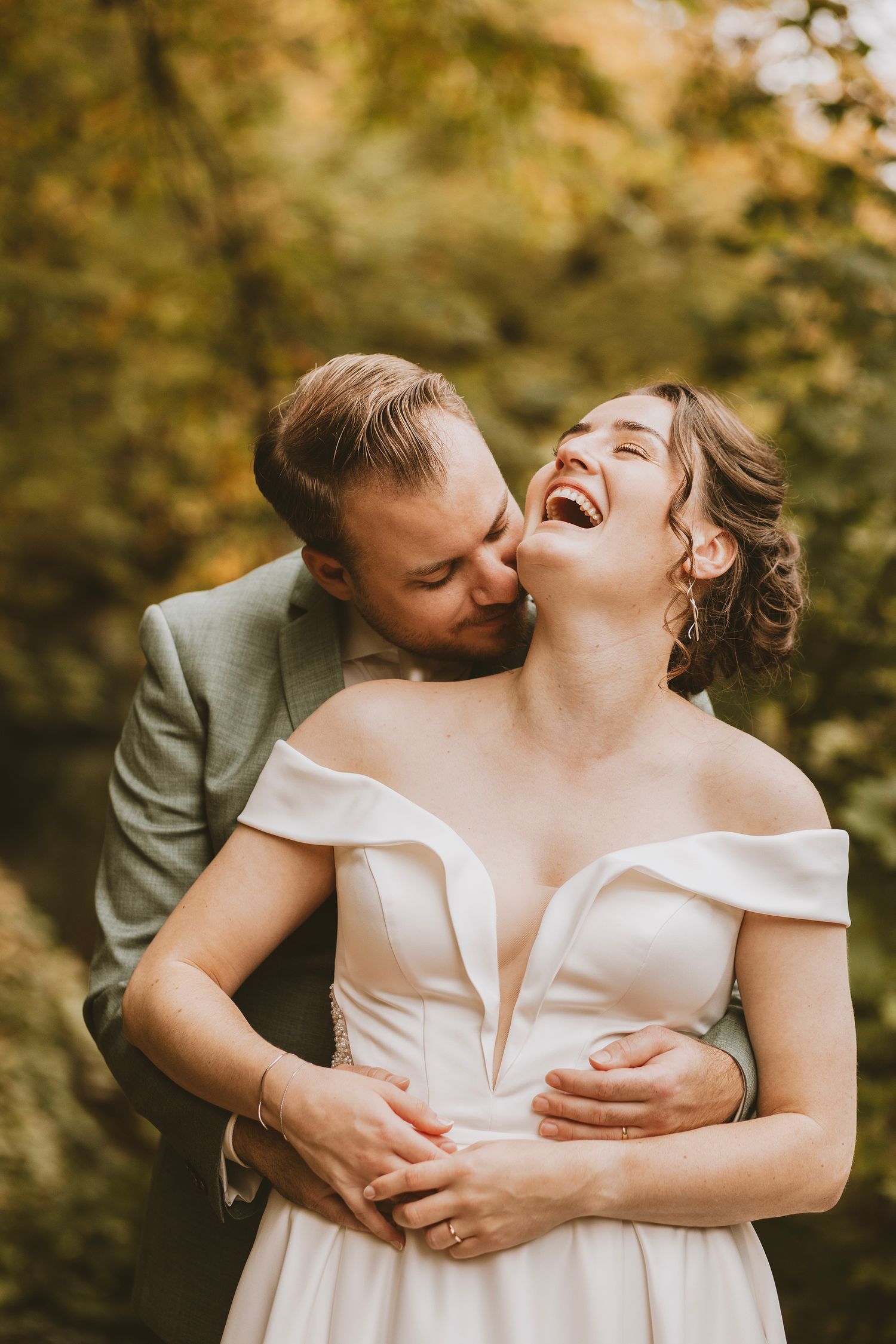 Joyful wedding couple sharing intimate moments in golden autumn light.