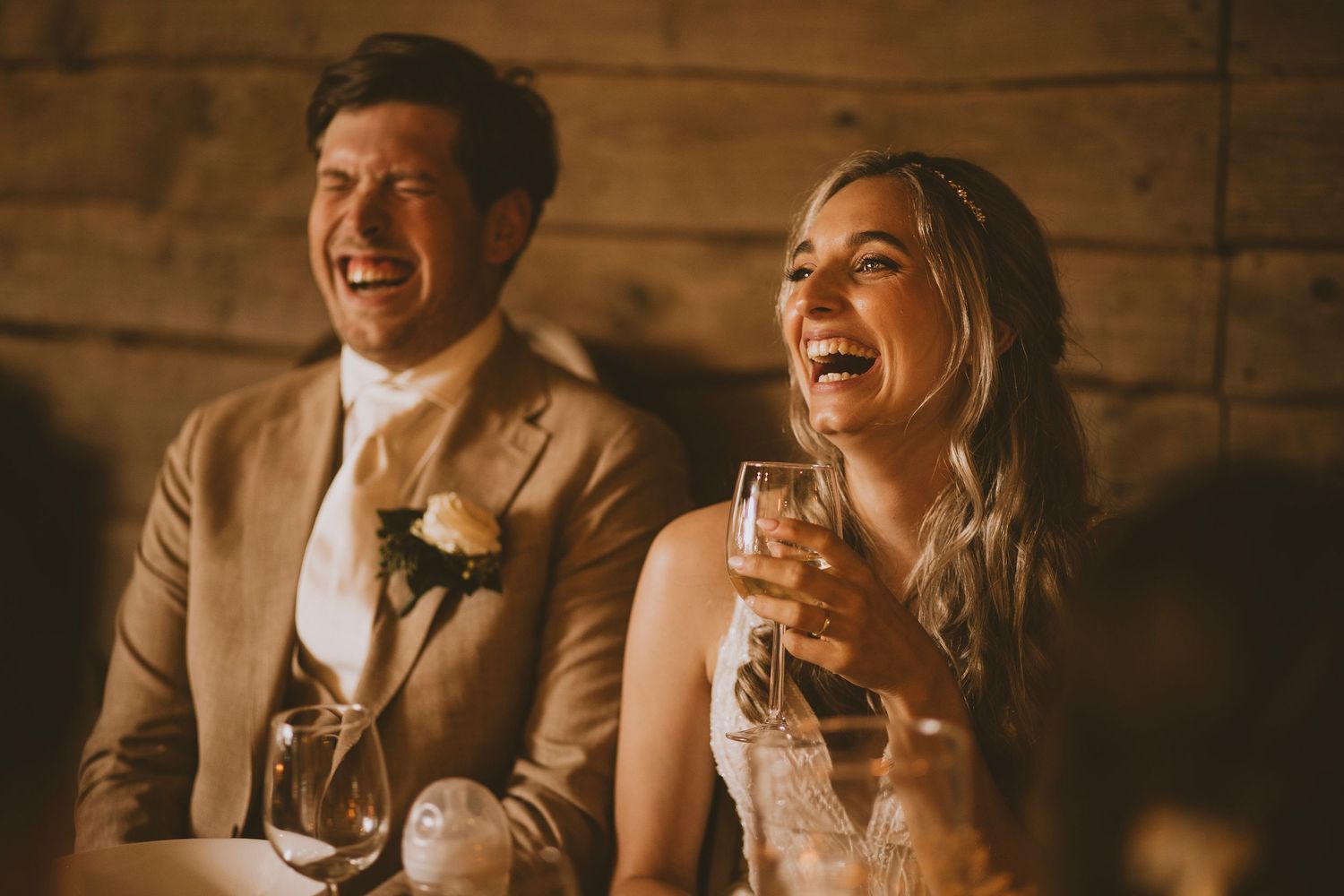 Lachend bruidspaar tijdens het diner op de trouwdag.