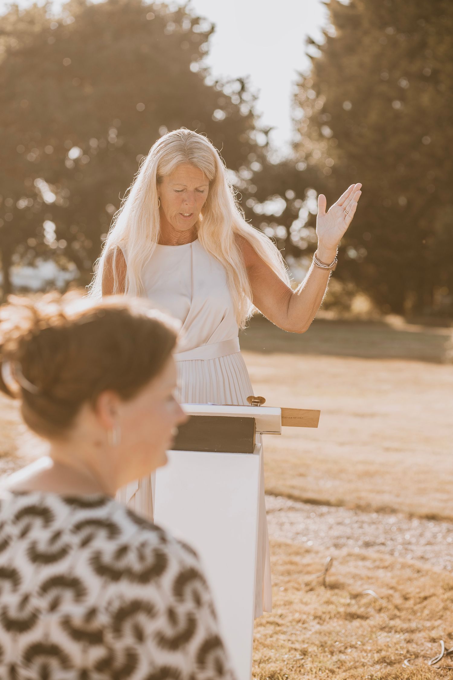 Wedding ceremony scene with a white piano outdoors in warm sunlight.