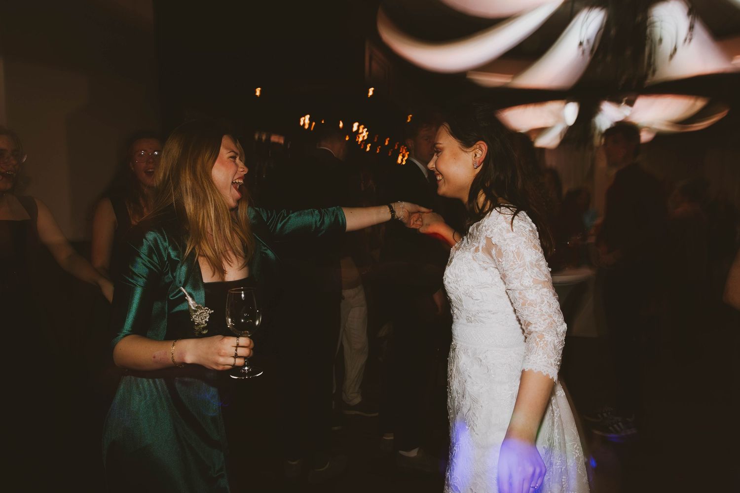 Guests dancing and celebrating at a dimly lit wedding reception party.