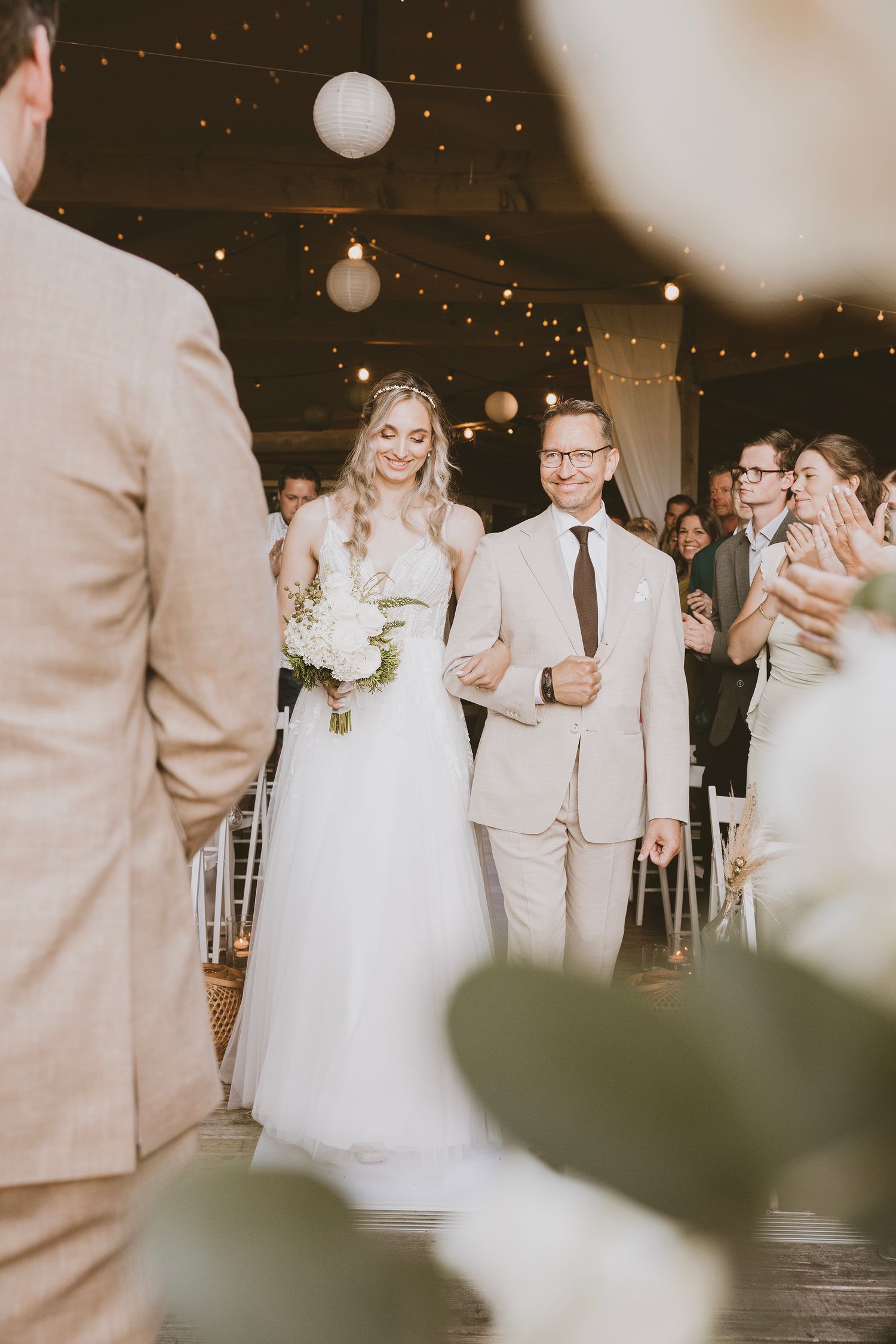 De bruid loopt met haar vader naar de ceremonie waar haar toekomstige man op haar wacht.