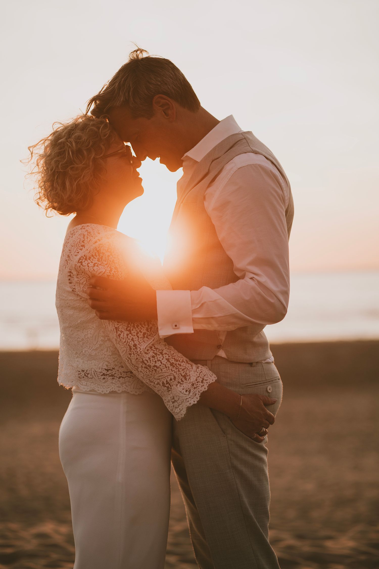 A romantic sunset silhouette of a couple embracing on their wedding day.