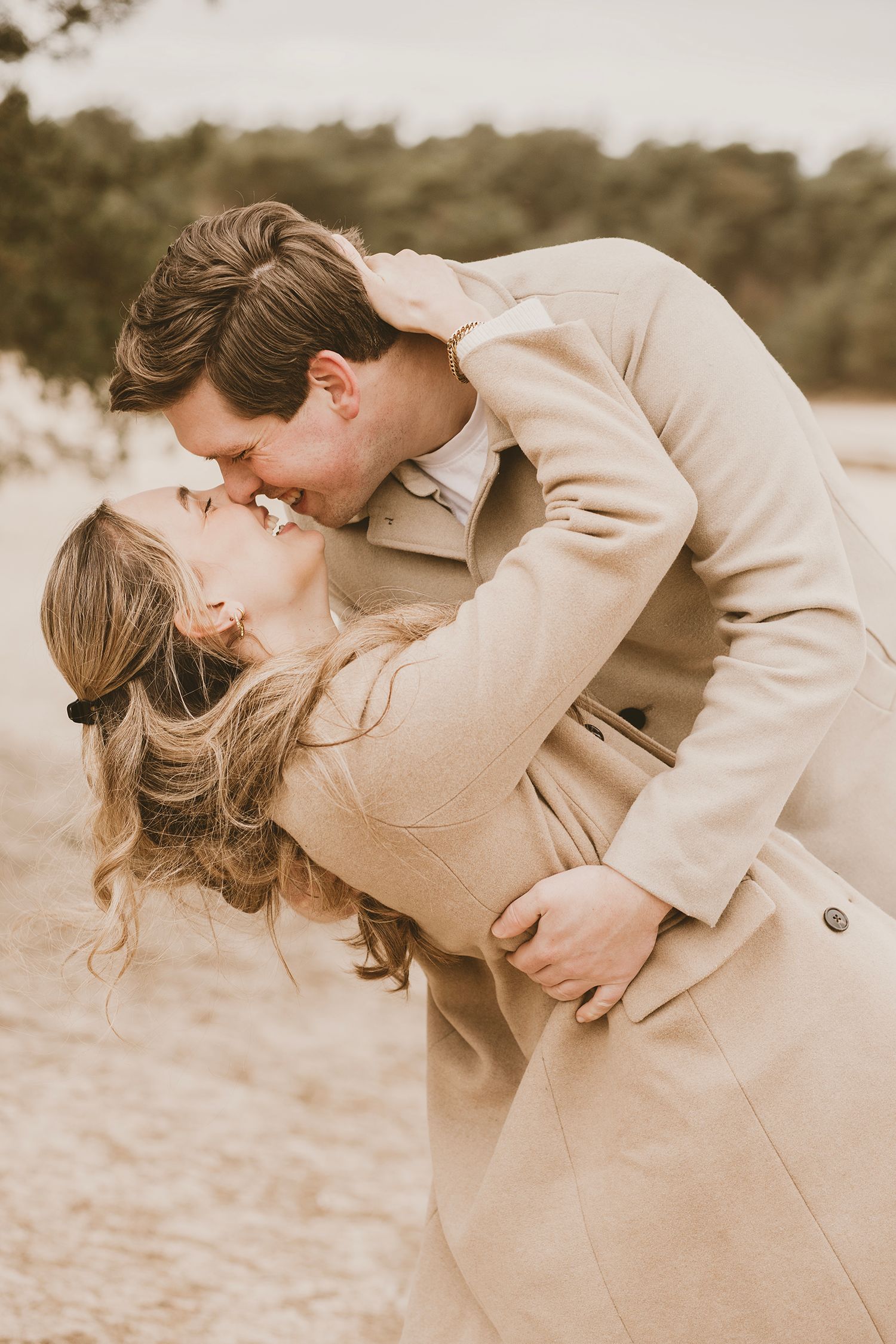 A romantic sepia-toned photo sequence showing a couple in beige coats embracing and dipping in an outdoor setting.