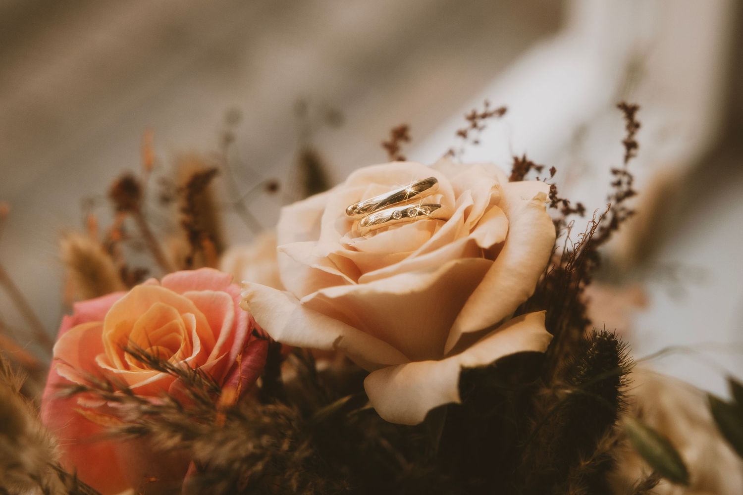 Delicate peach and pink roses in a wedding floral arrangement.