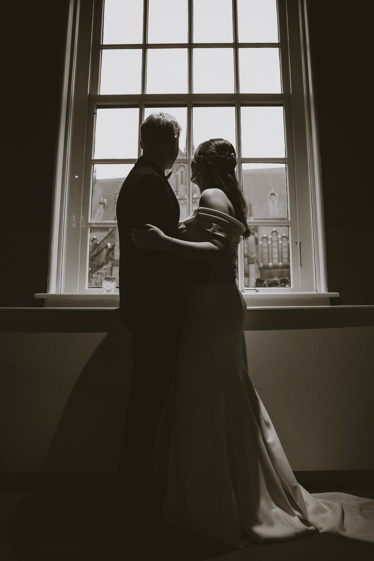 A series of black and white photos showing a silhouetted figure gazing through a window in a dark room.