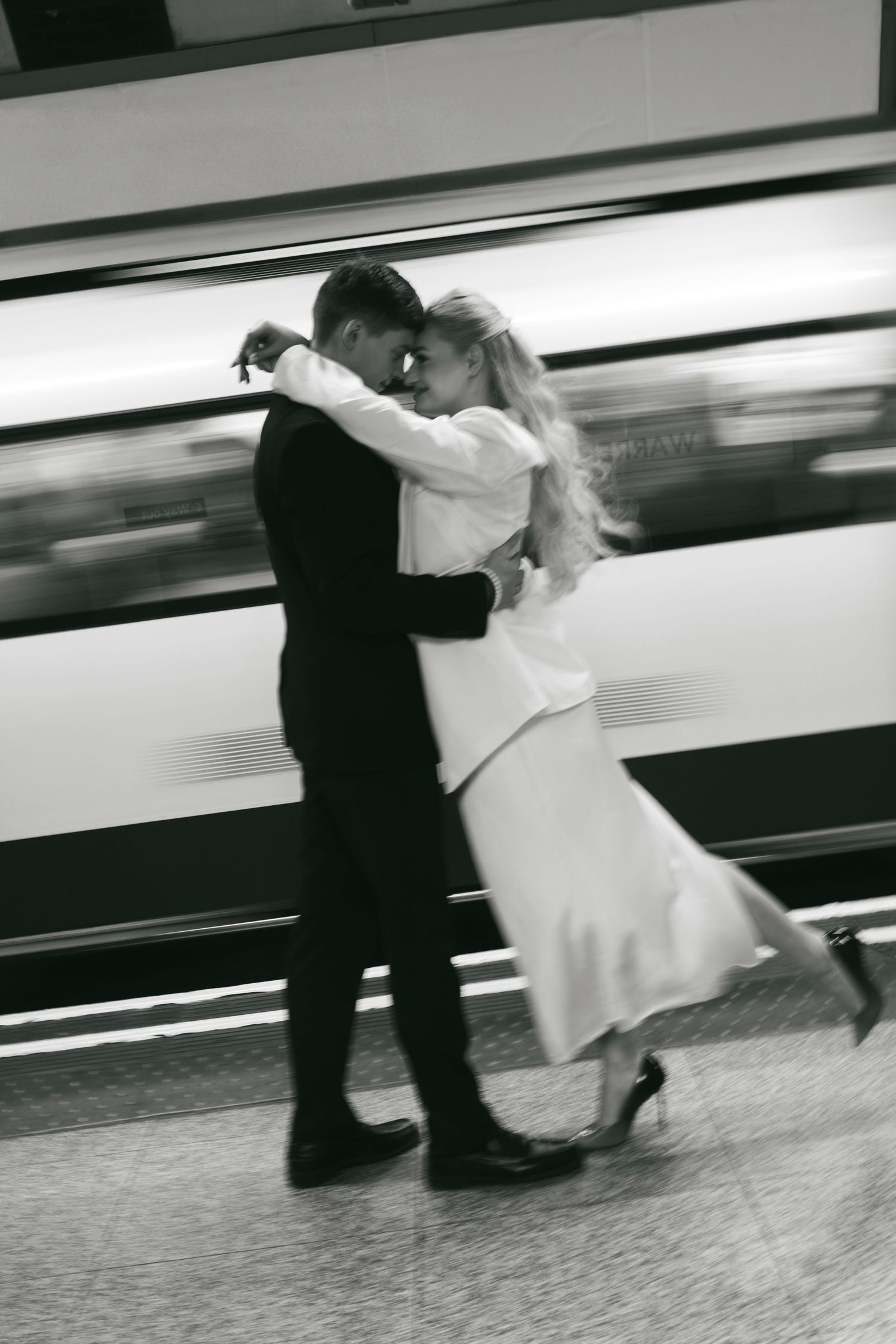Couple on a London Underground platform with a train passing behind them.