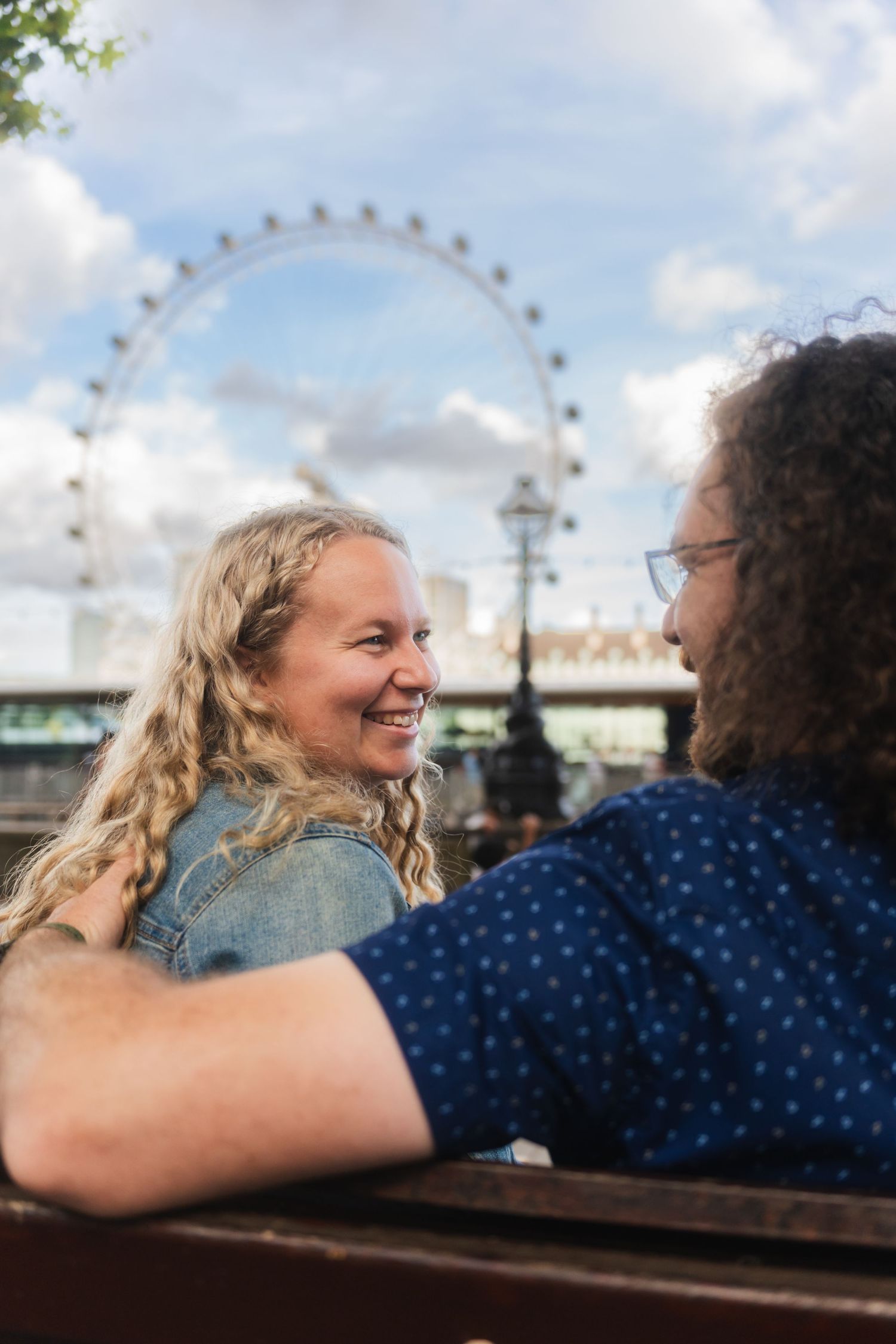 Close-up of the couple sitting on a bench with the London Eye blurred in the background captured by UK Photographer @lyfphotos