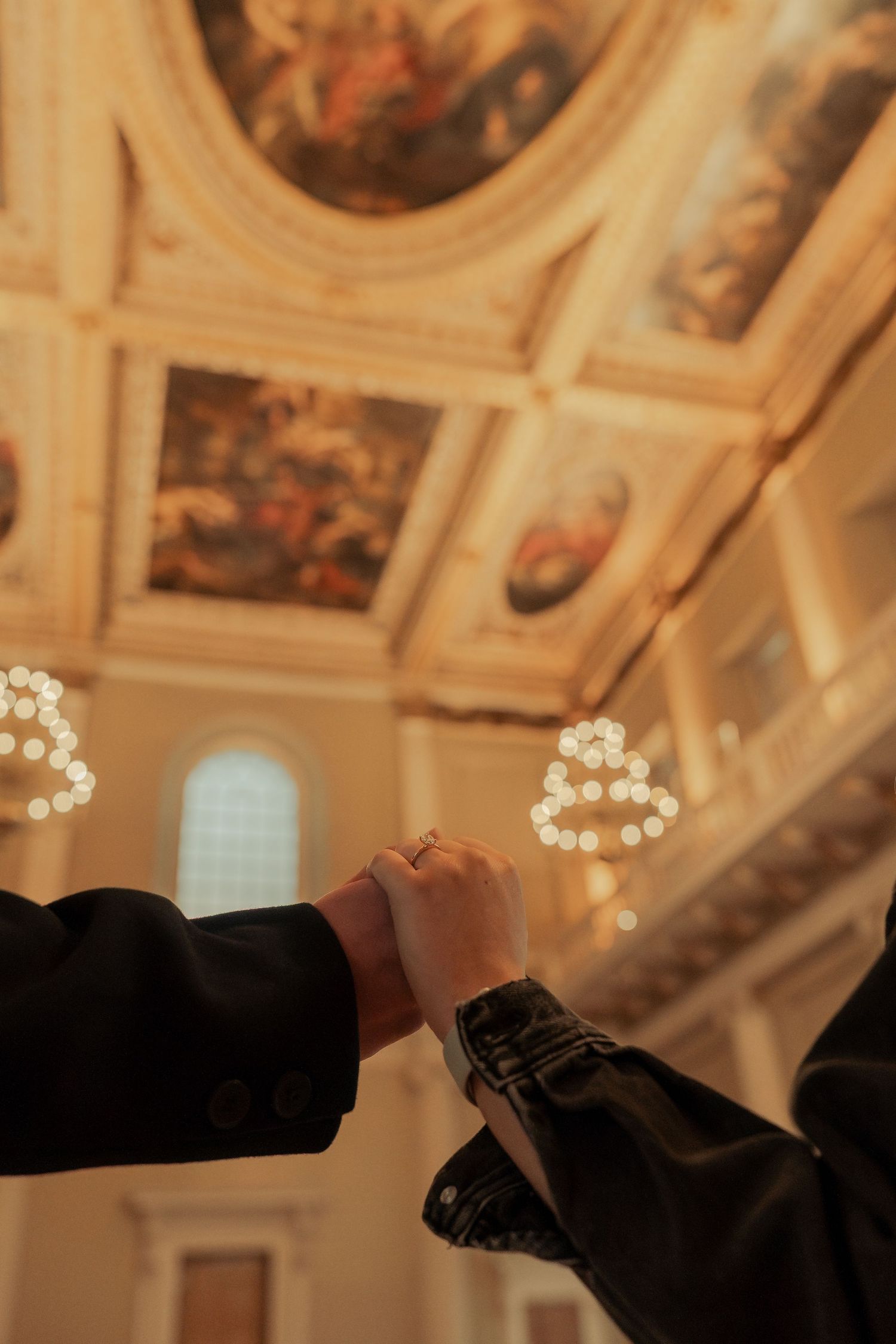 Close-up of engagement ring inside Banqueting House London with chandelier lights in the background