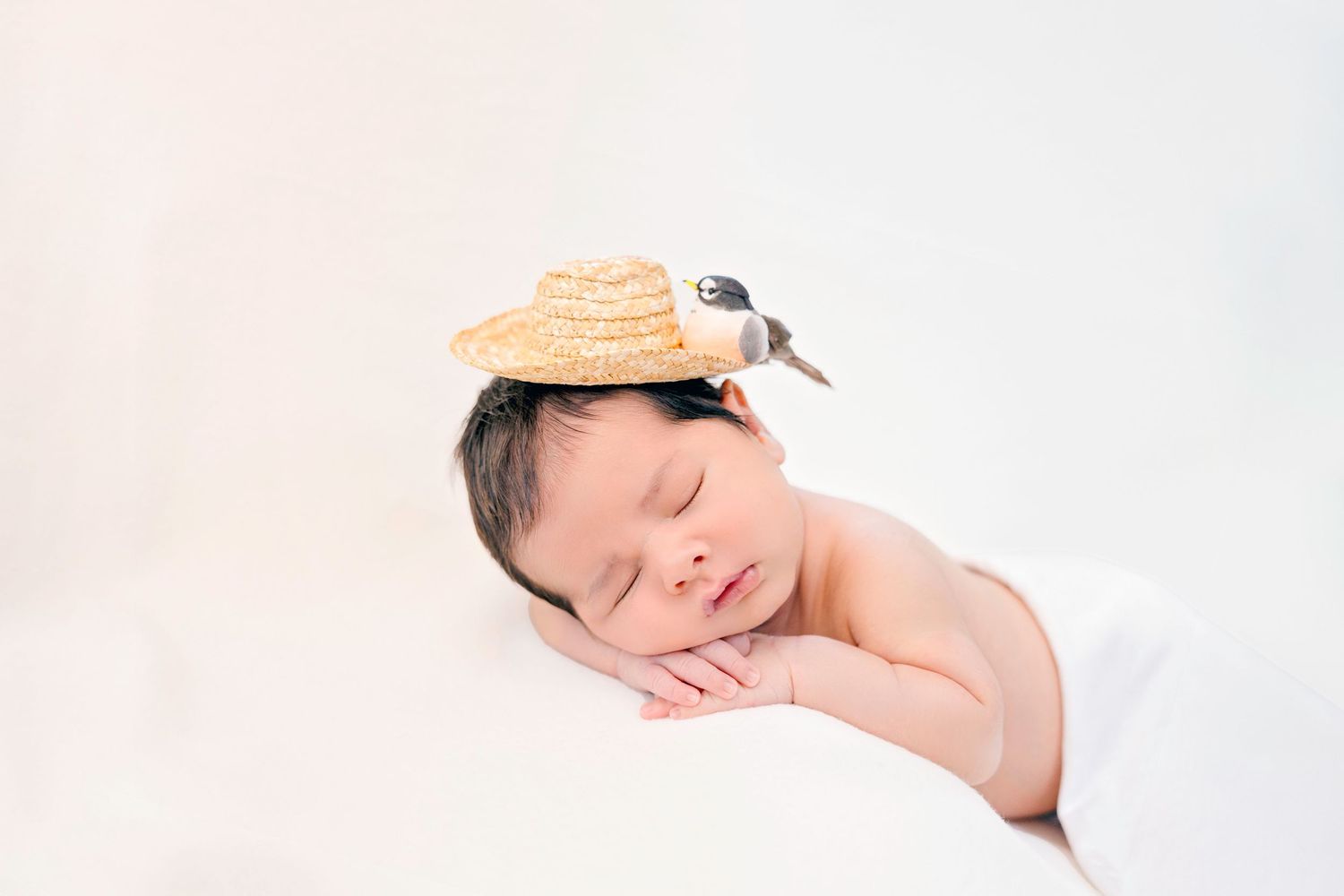 Minimalist newborn photography with soft white backdrop and gentle side lighting.
