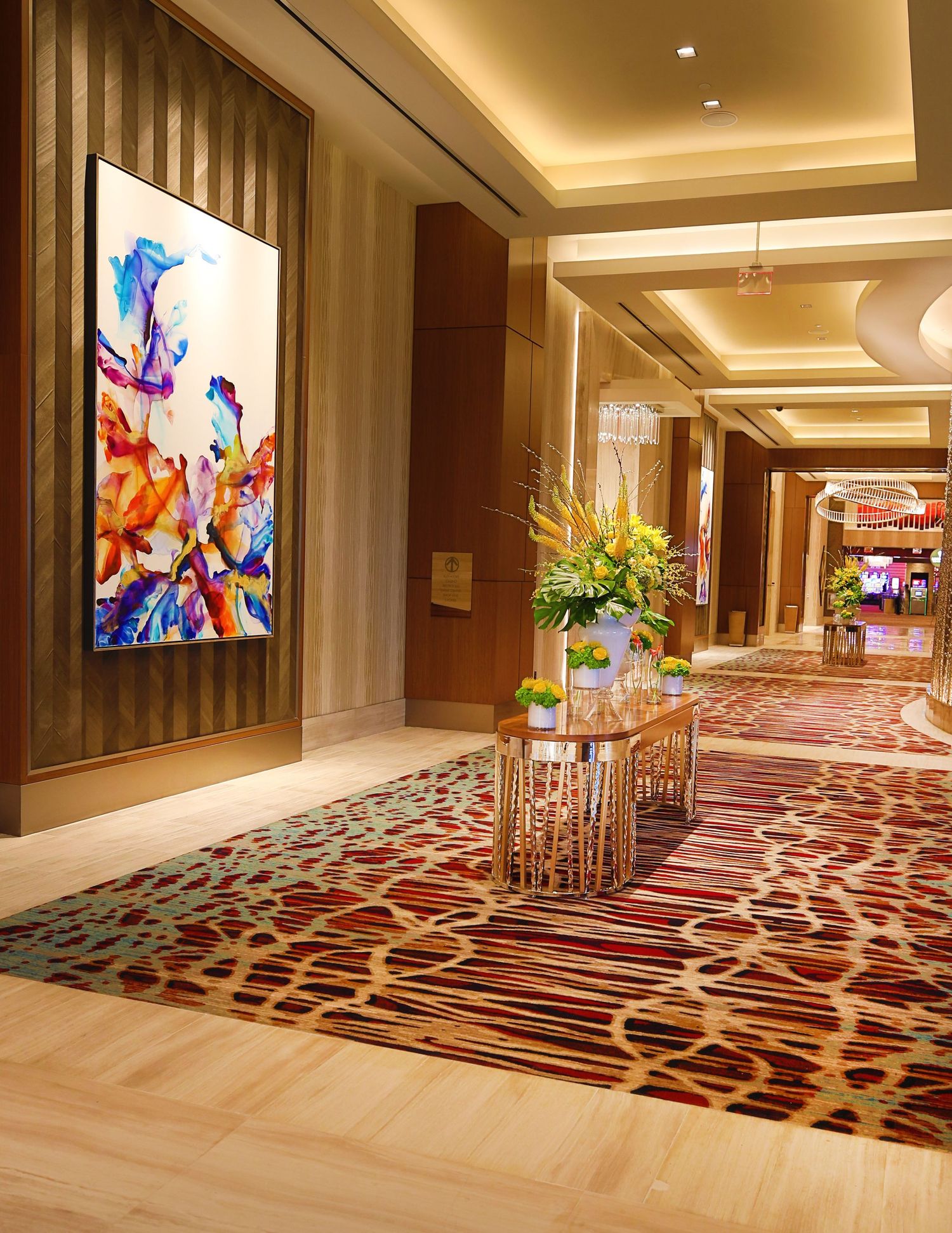 Elegant hotel corridor with patterned carpet, recessed lighting, and modern artwork.