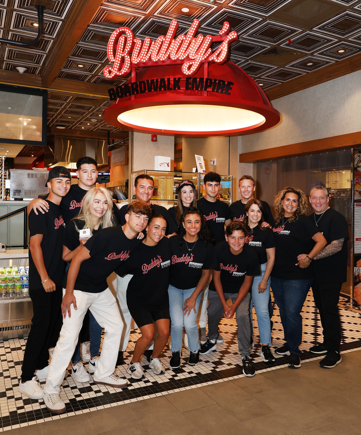 Restaurant staff in black uniforms posing together in front of Boardwalk Empire signage.