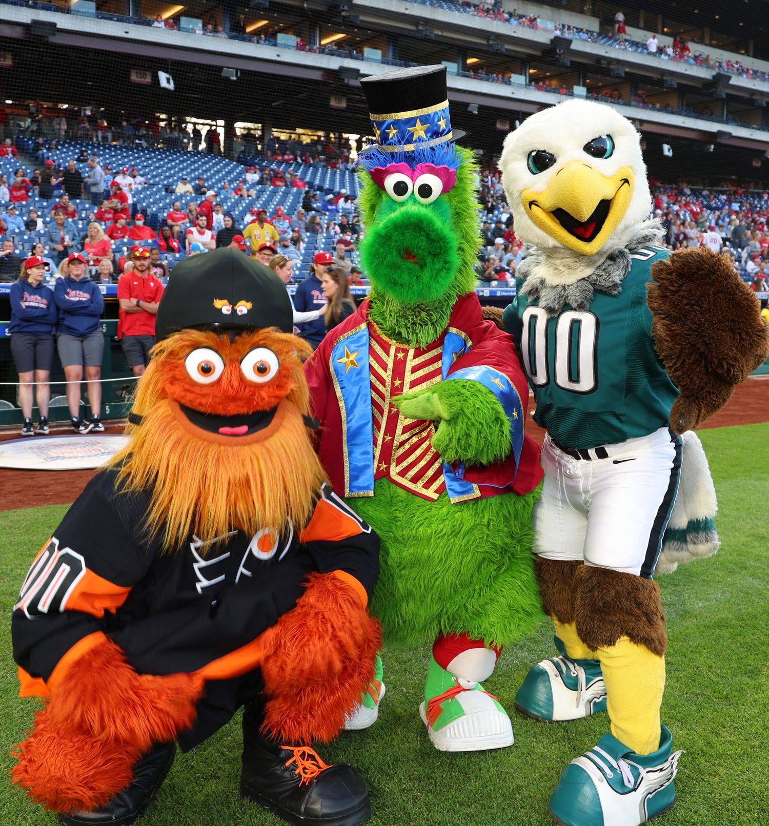 Sports mascots including furry characters in team uniforms posing together on a field.