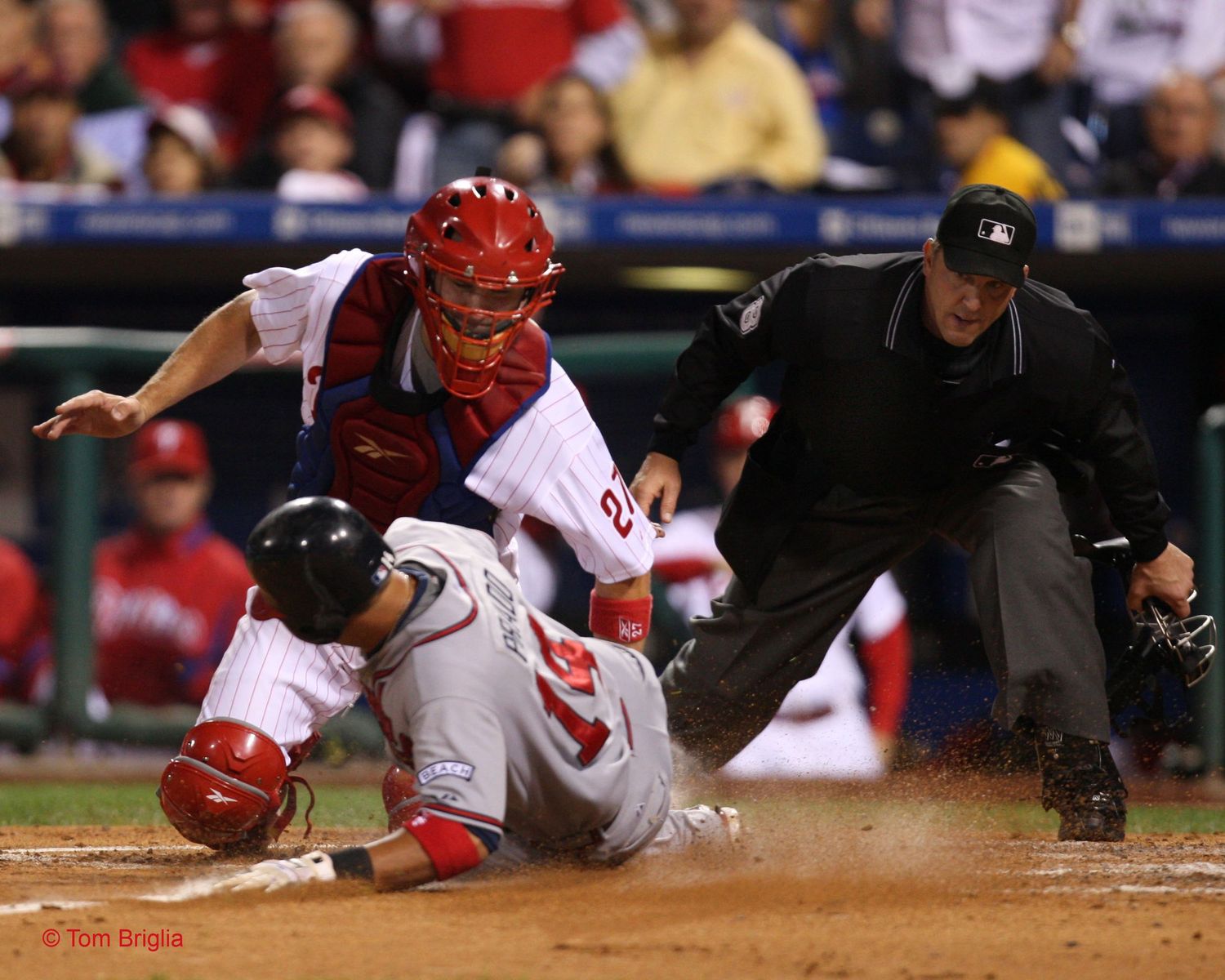 Baseball catcher attempts tag at home plate as runner slides in with umpire observing.