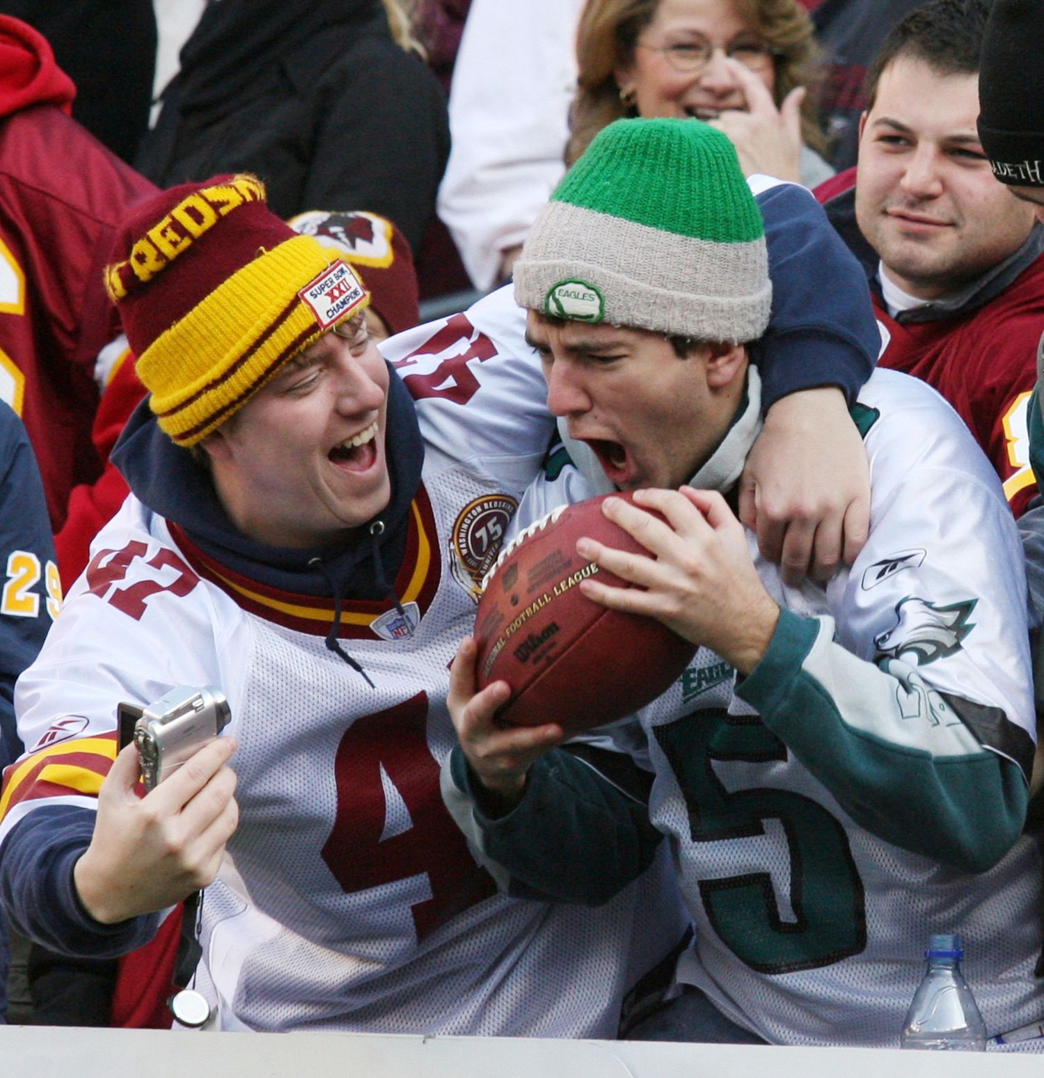 Sports fans in winter hats celebrating and cheering at an outdoor event.