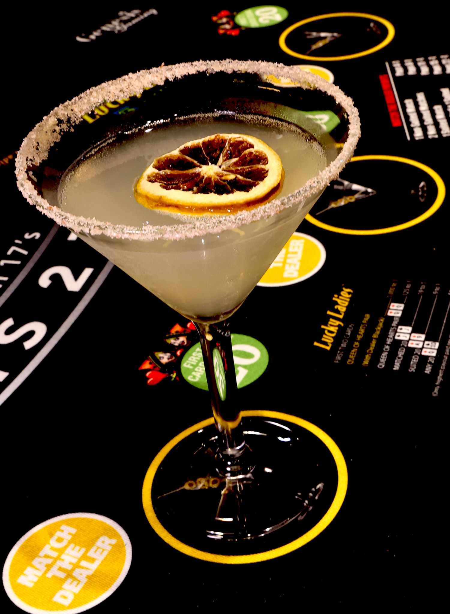 Margarita cocktail with salt rim and citrus garnish served on a dark bar surface.