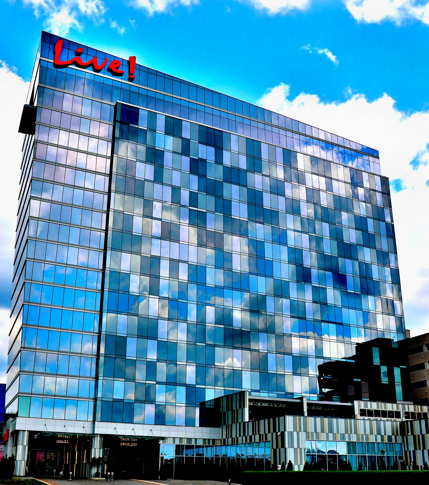 Modern glass office building with reflective blue windows and angular architecture against bright sky.