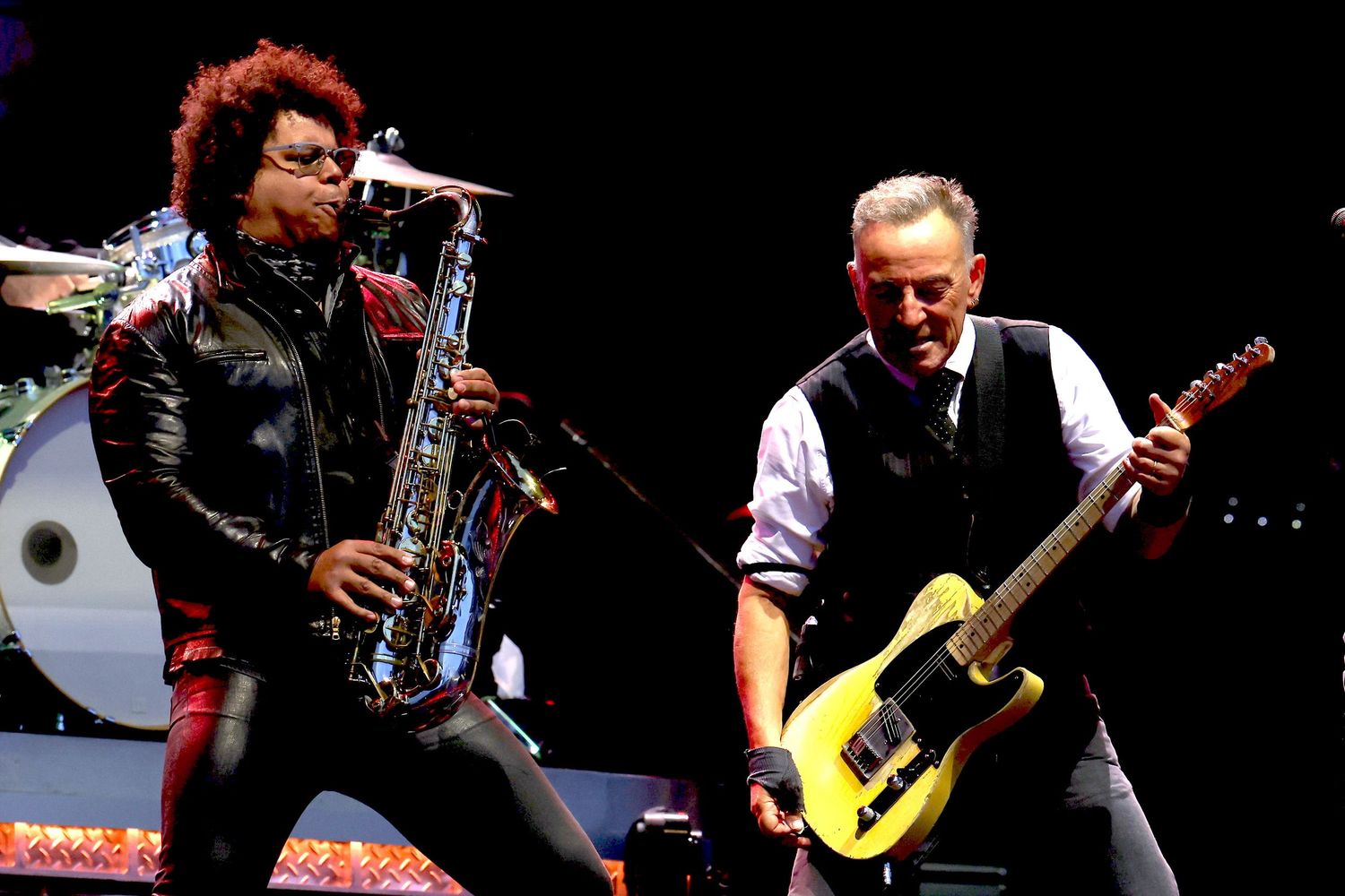 Rock band members performing energetically on stage with guitars and instruments.