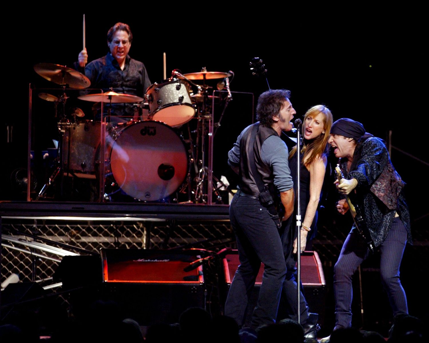 Musicians performing together on dimly lit concert stage with instruments.