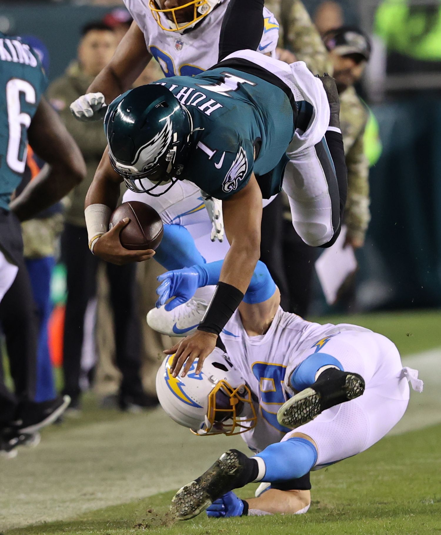 Football players collide and tumble during an intense tackle sequence on the field.