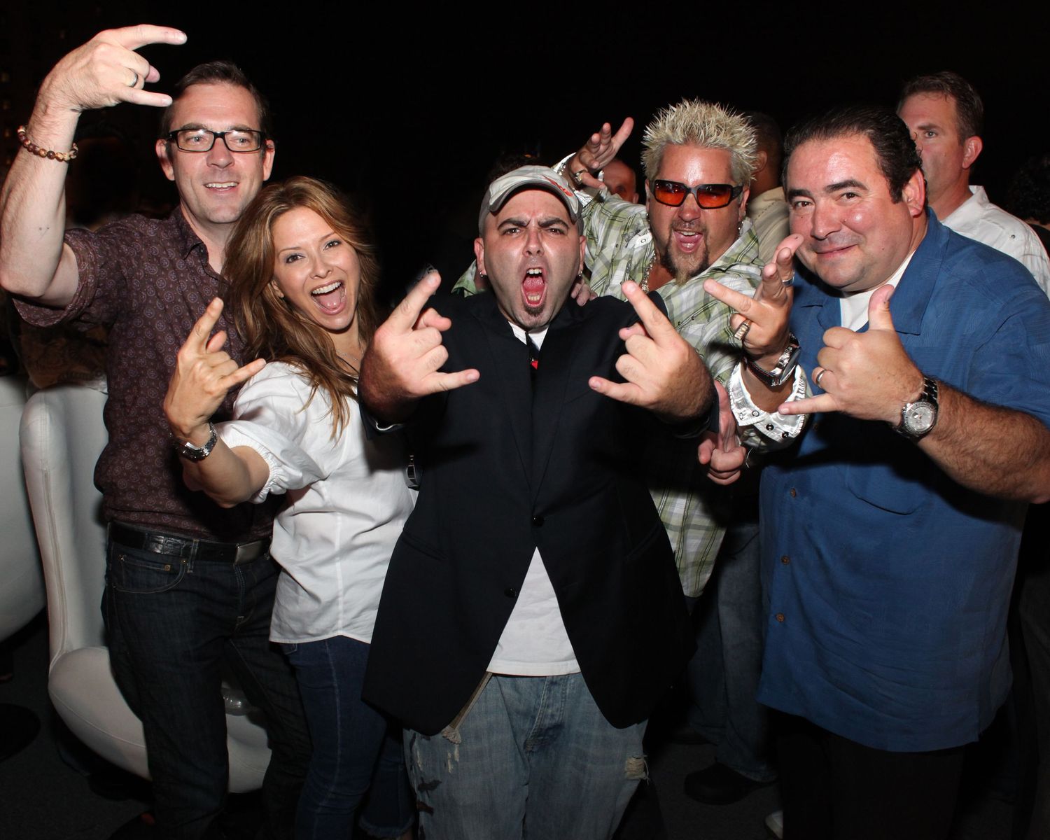 Group of people celebrating and taking photos at a dark venue.