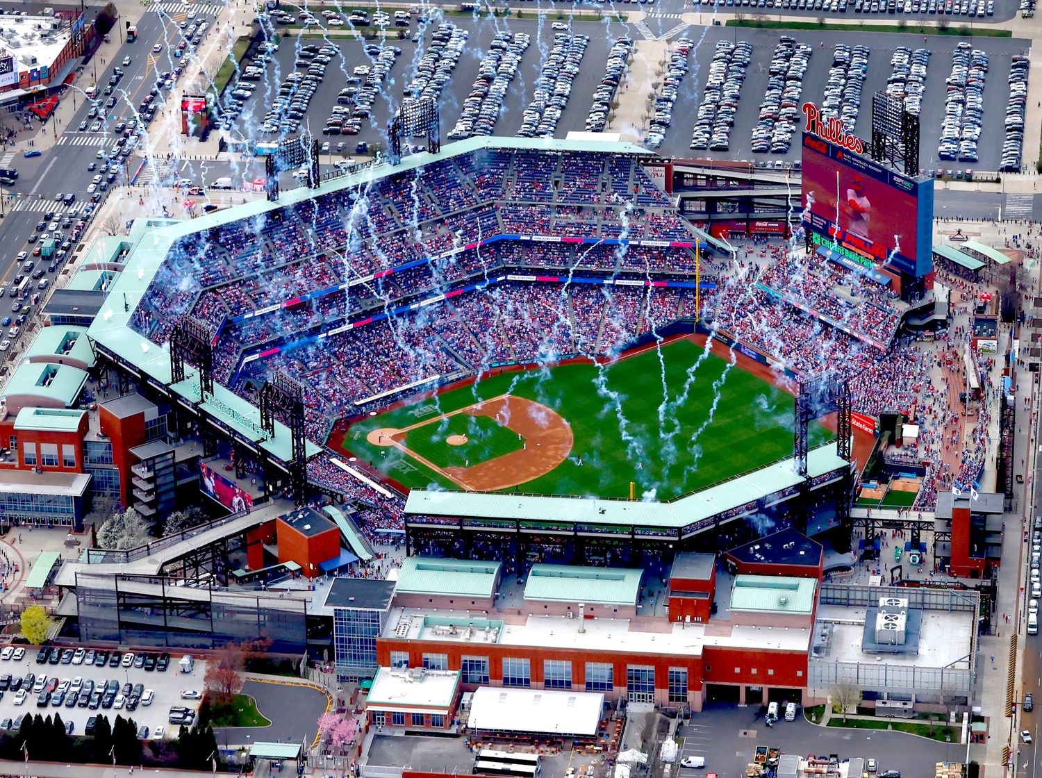Aerial view of baseball stadium with packed crowd during daytime event.