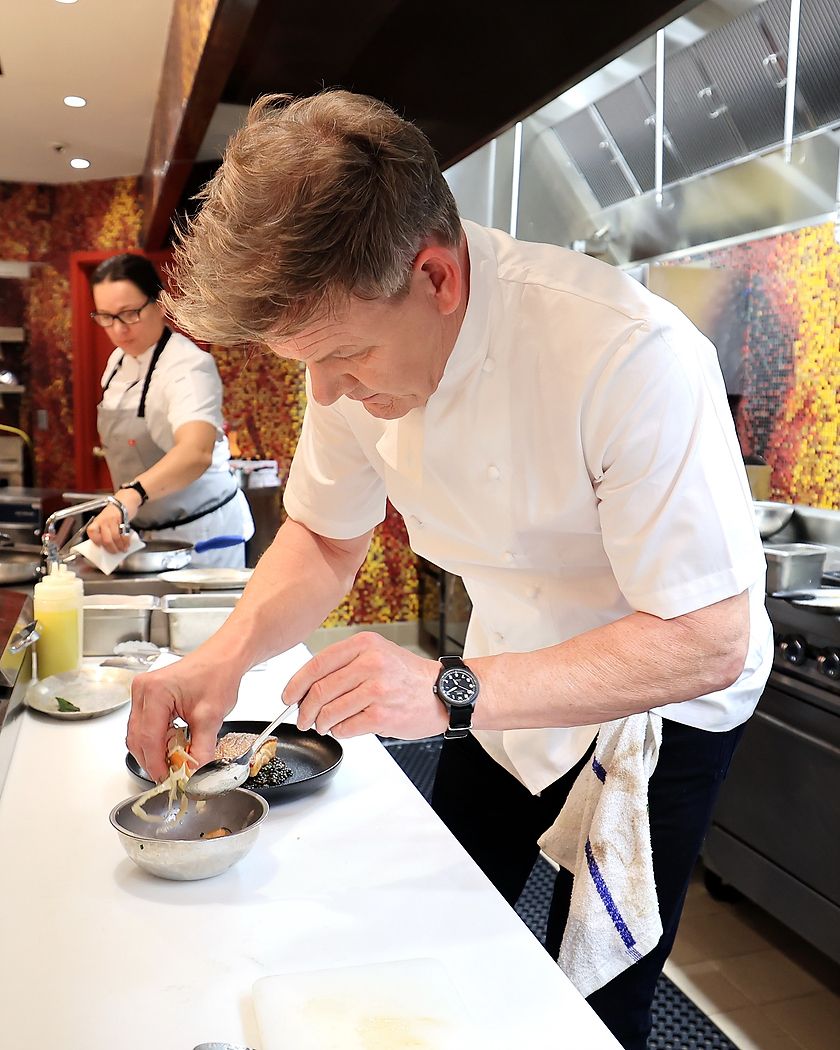 Chef in white uniform carefully preparing ingredients in professional kitchen.