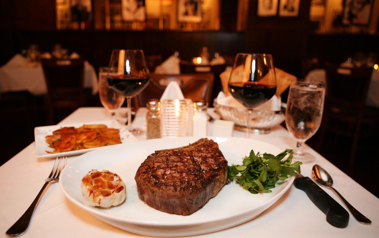 Fine dining table setting with wine glasses and perfectly plated steaks.