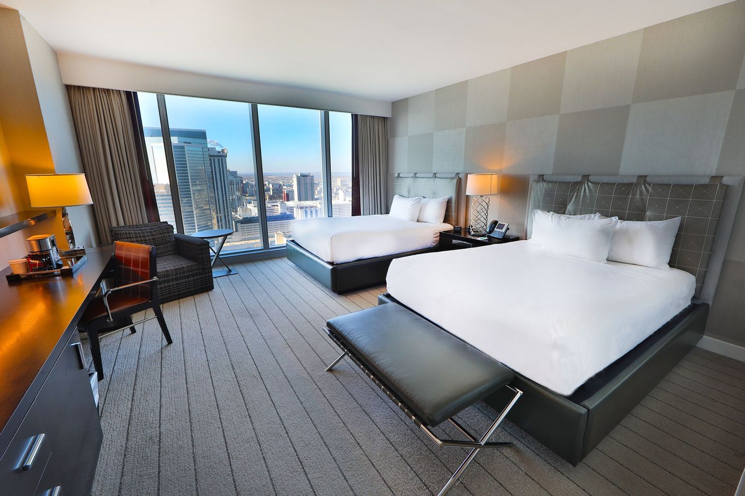 Luxurious hotel room with panoramic city views and modern furnishings.