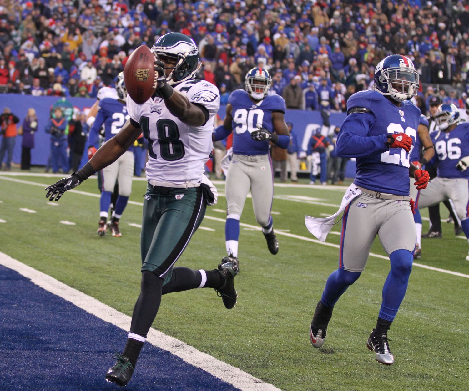 Football players from the Eagles and Giants compete in a dynamic sequence of game action near the end zone.