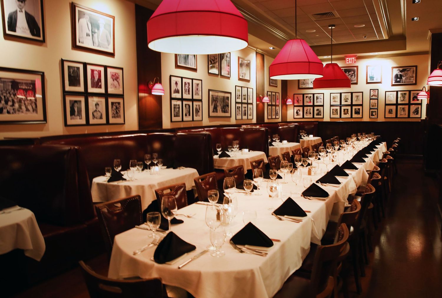 Formal dining room with long white-clothed tables and red pendant lamps.