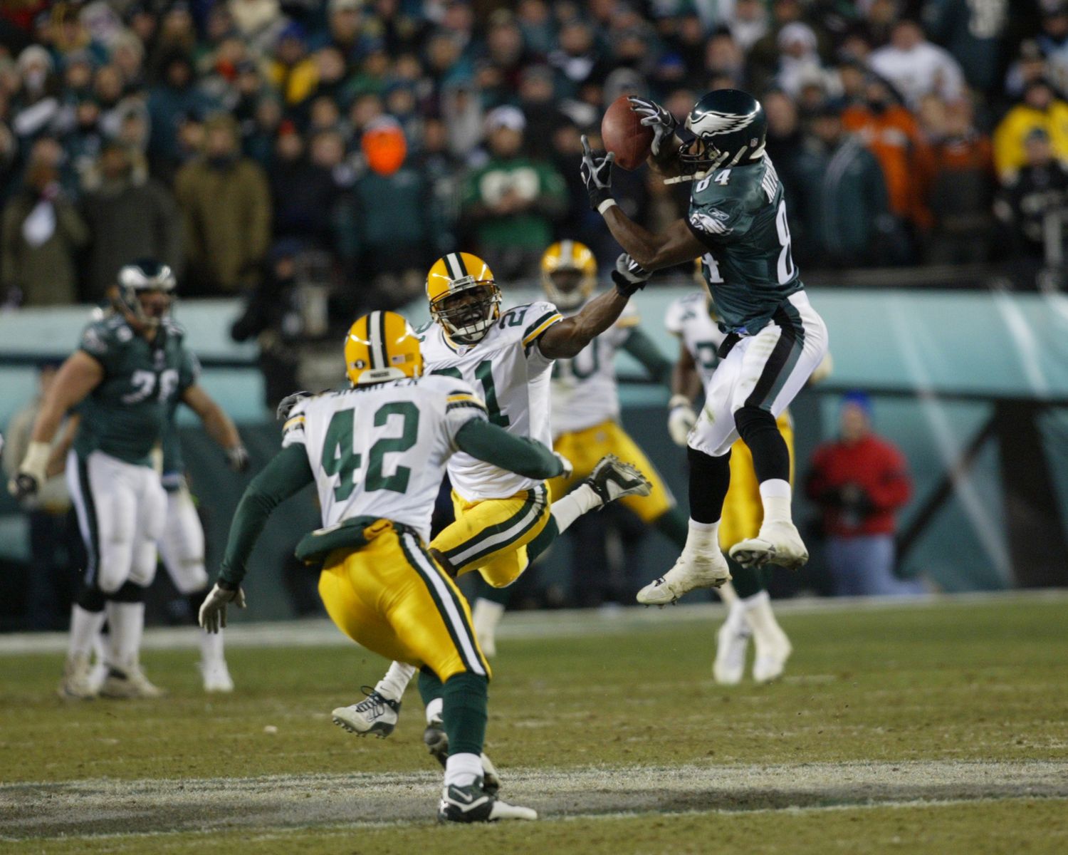 Green Bay Packers and Philadelphia Eagles players battling for possession during an NFL game.