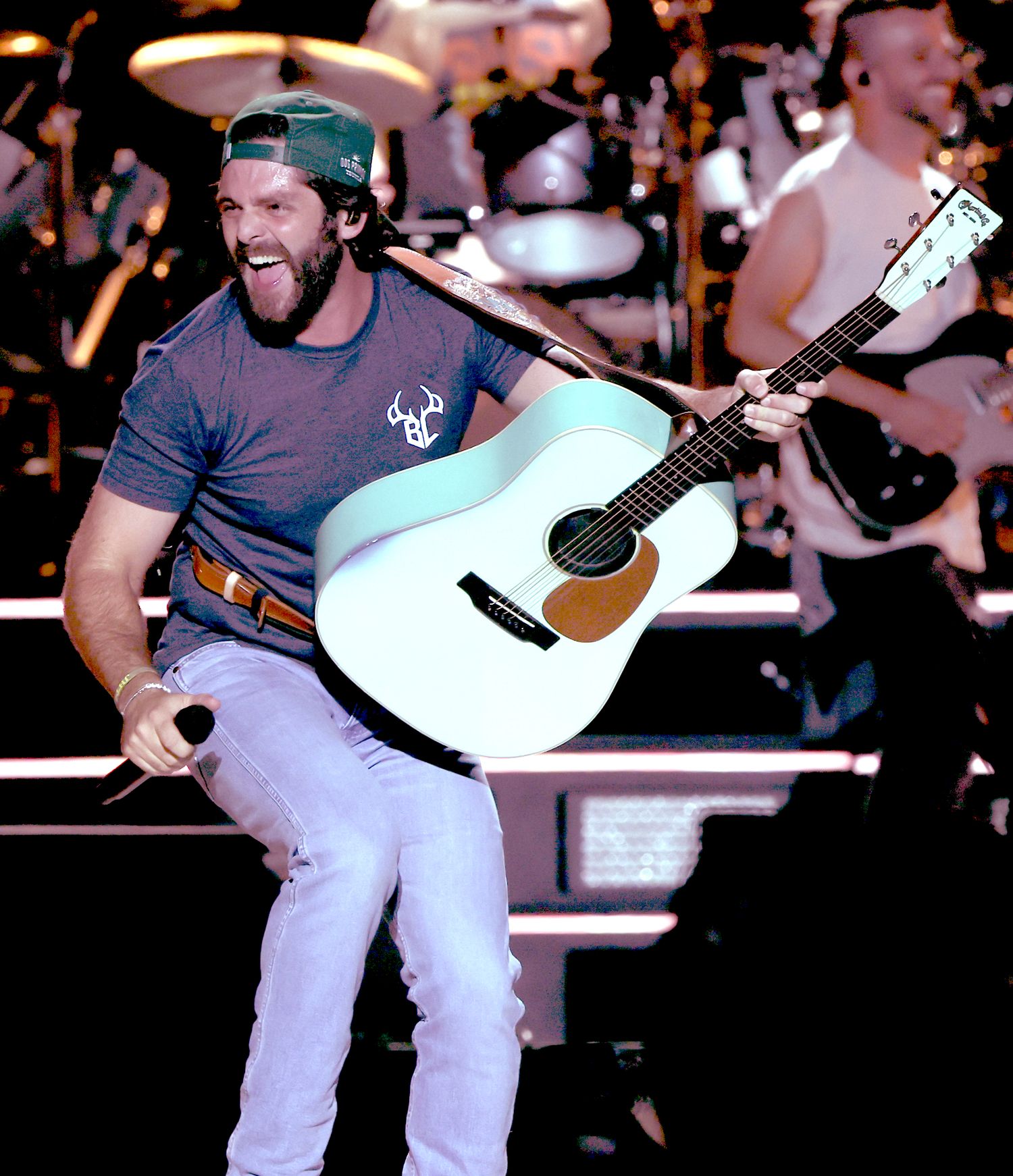 Country musician performing enthusiastically with acoustic guitar on concert stage.