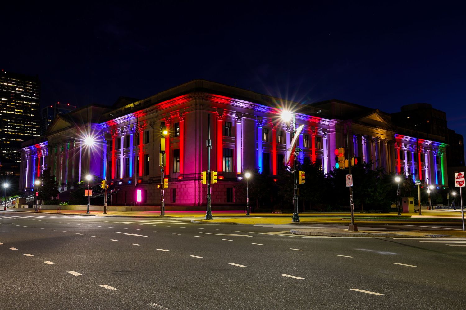 Row of buildings illuminated with colorful LED lights at night.