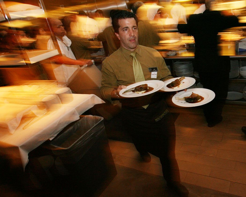 Diners enjoying a meal in a dimly lit restaurant with warm ambient lighting.