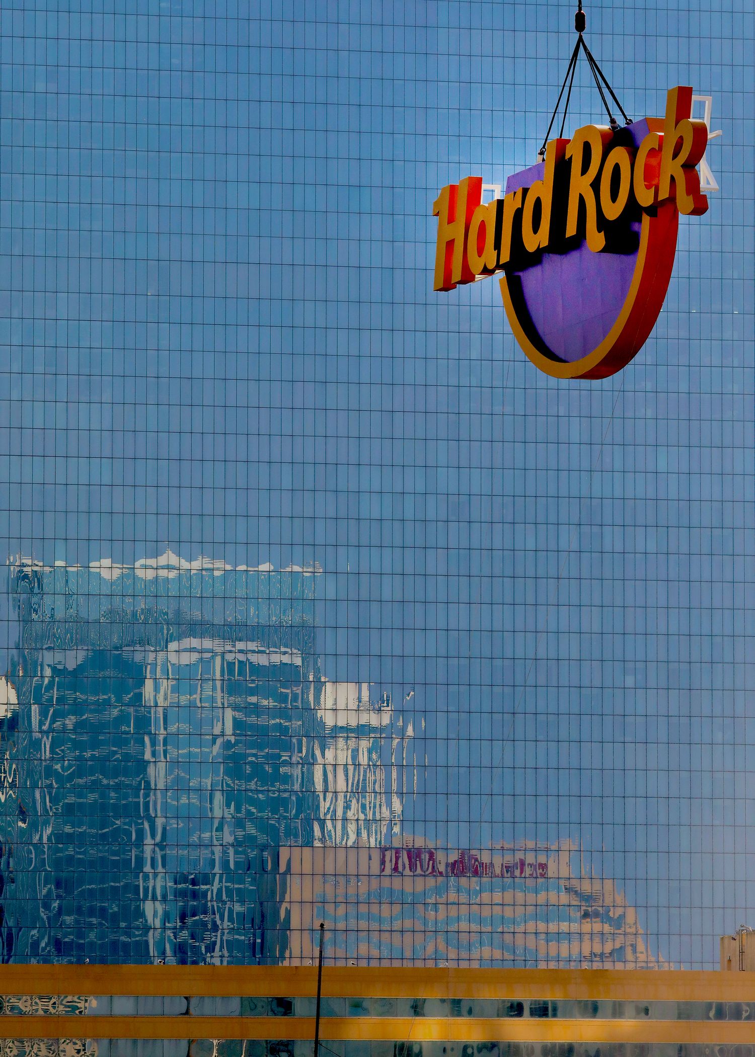 Hard Rock logo reflected on modern glass building exterior.