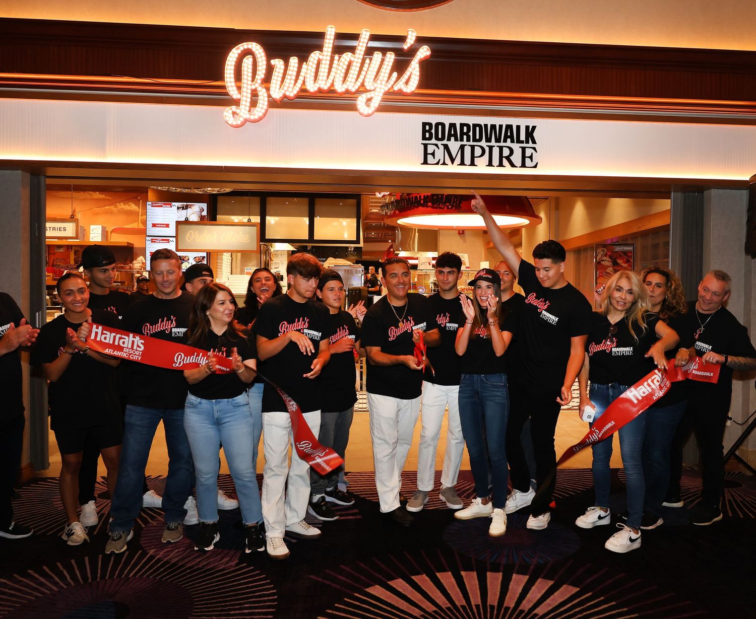 People arranged in a falling domino pattern inside a restaurant with illuminated signage.