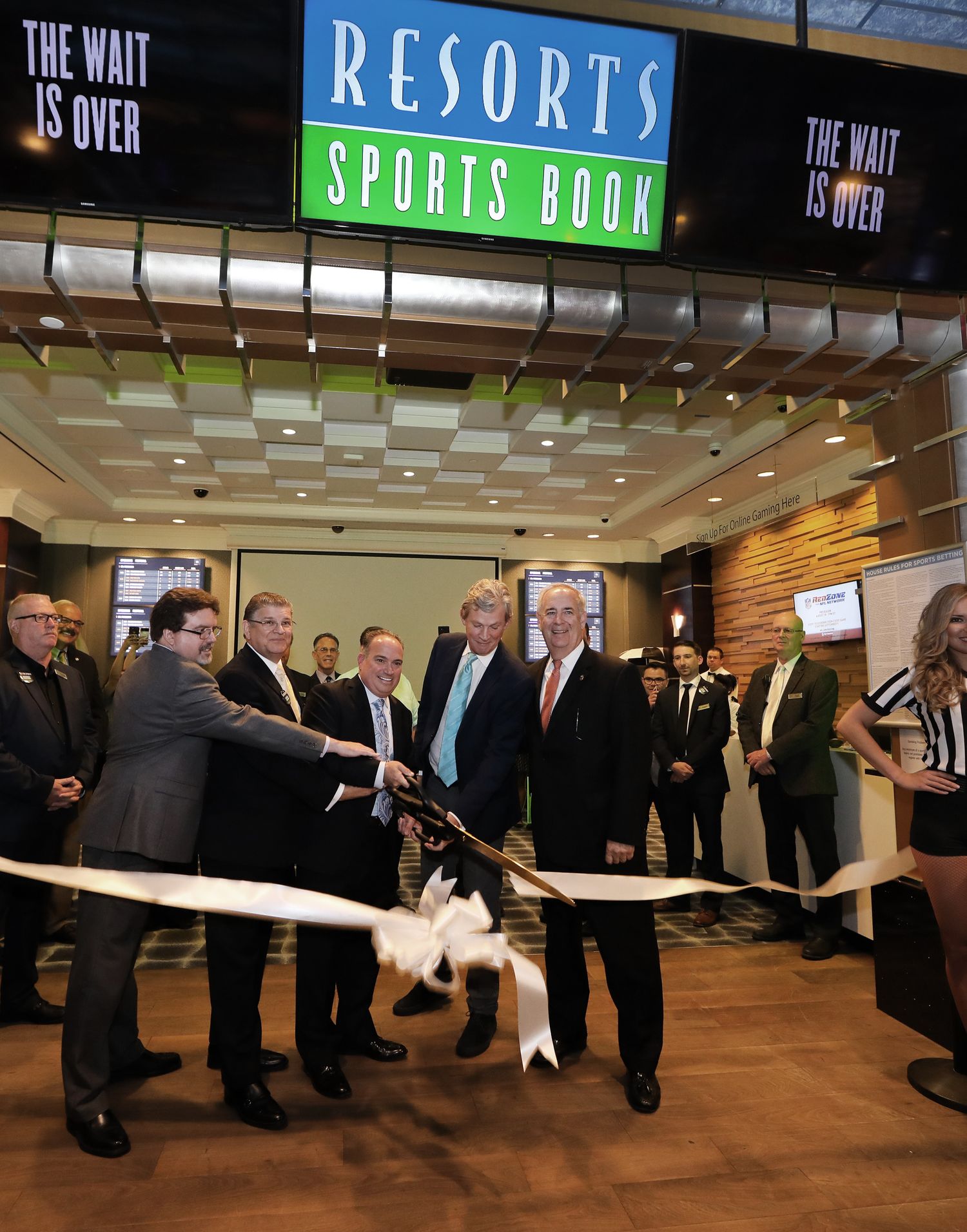 Group of business professionals lined up in a sports book or casino setting.
