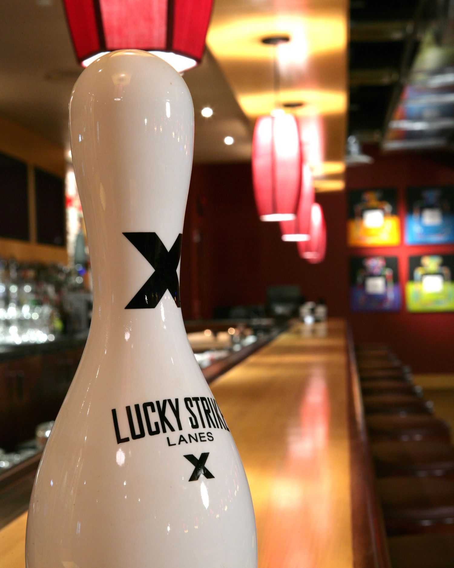 Bowling pins with Lucky Strike branding displayed in a dimly lit bowling alley.