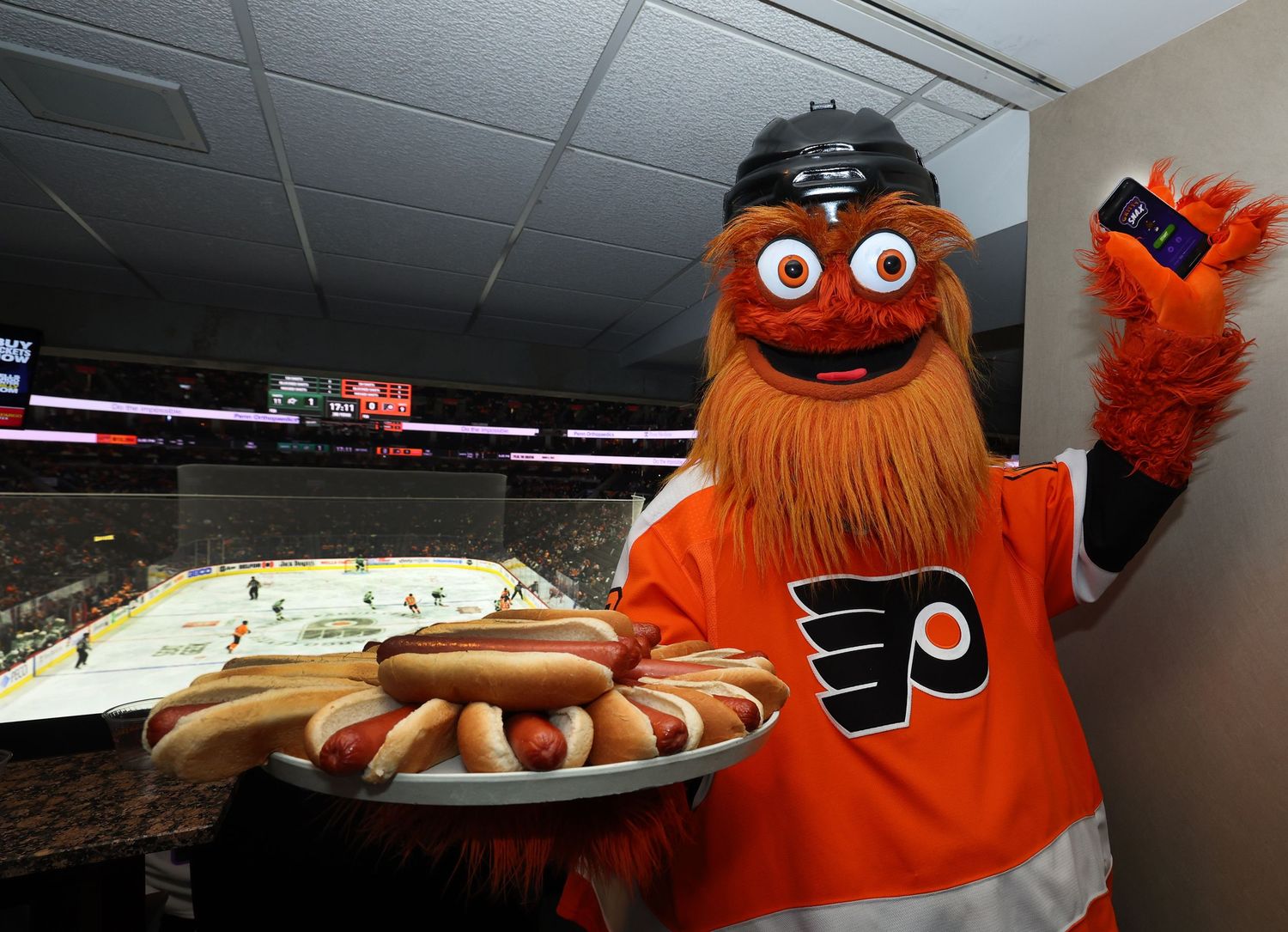Orange mascot characters serving food and interacting with guests at indoor event.