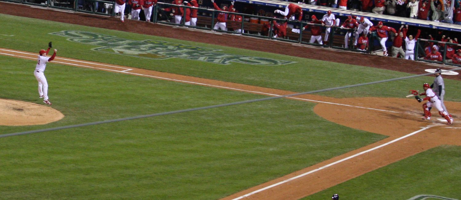 Baseball players on field during game with first base and infield grass visible.