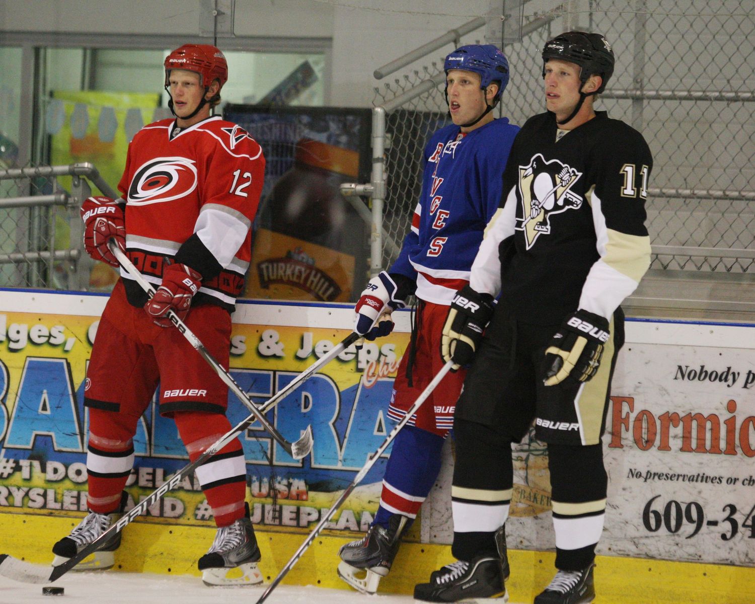 Three hockey players from different teams stand together on the ice during a game.