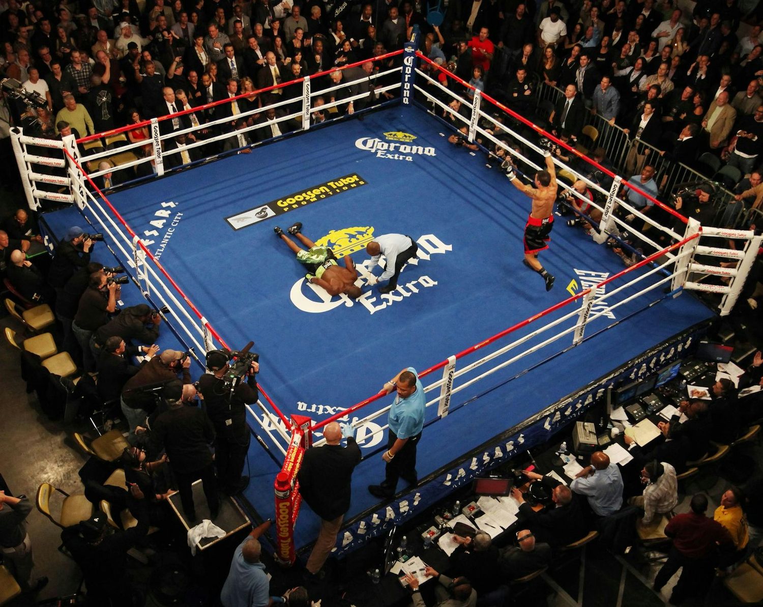 Professional boxing match in a ring surrounded by spectators in a packed arena.