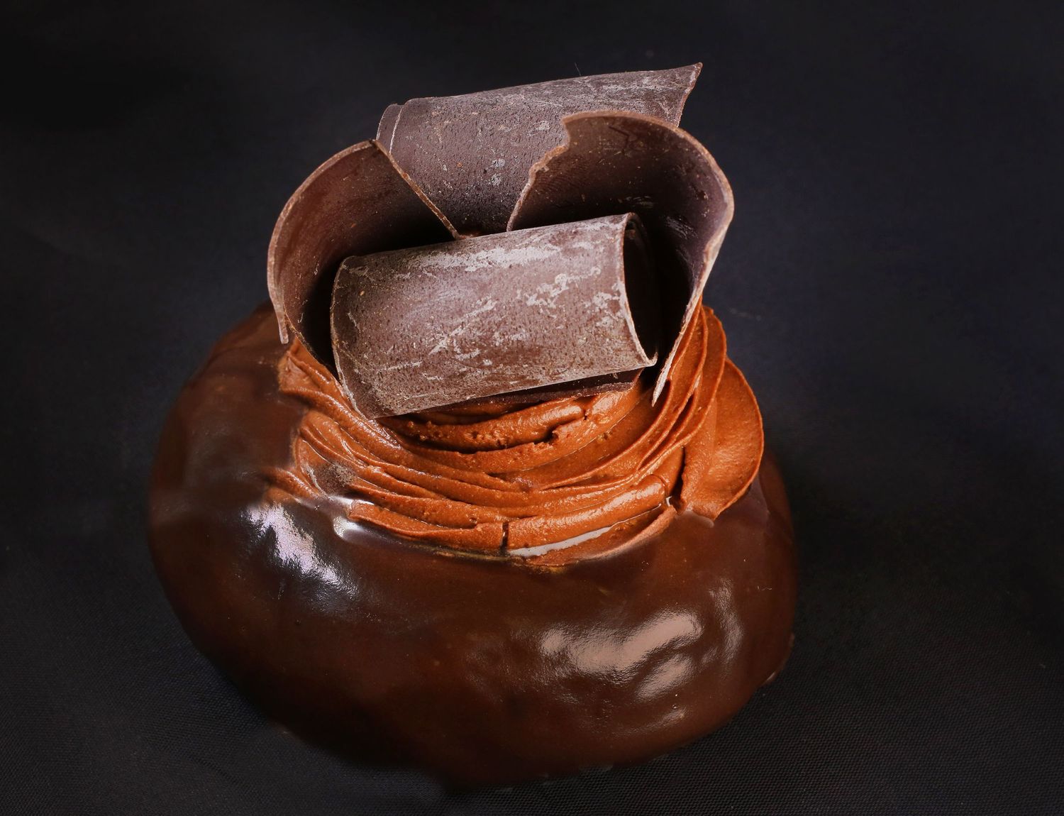 Melted chocolate being poured into a dark chocolate shell against black background.