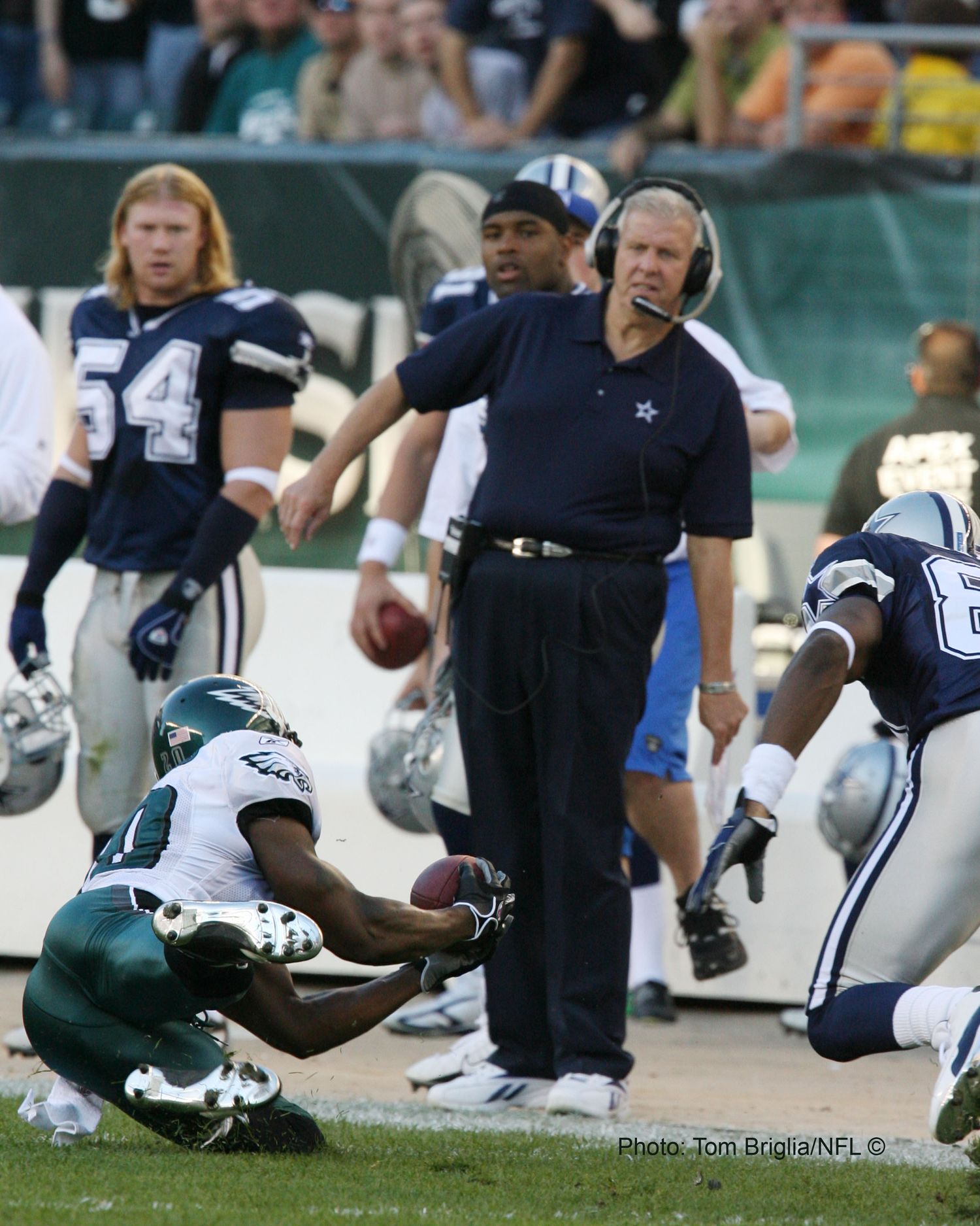 Football players from the Cowboys and Eagles diving for a loose ball on the field during an NFL game.