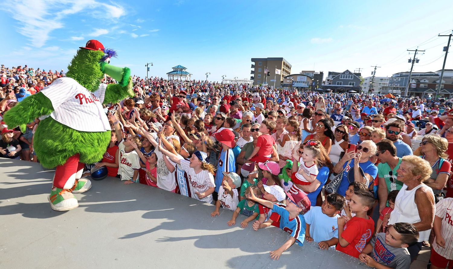 Large crowd of spectators watching an outdoor event on a sunny day.