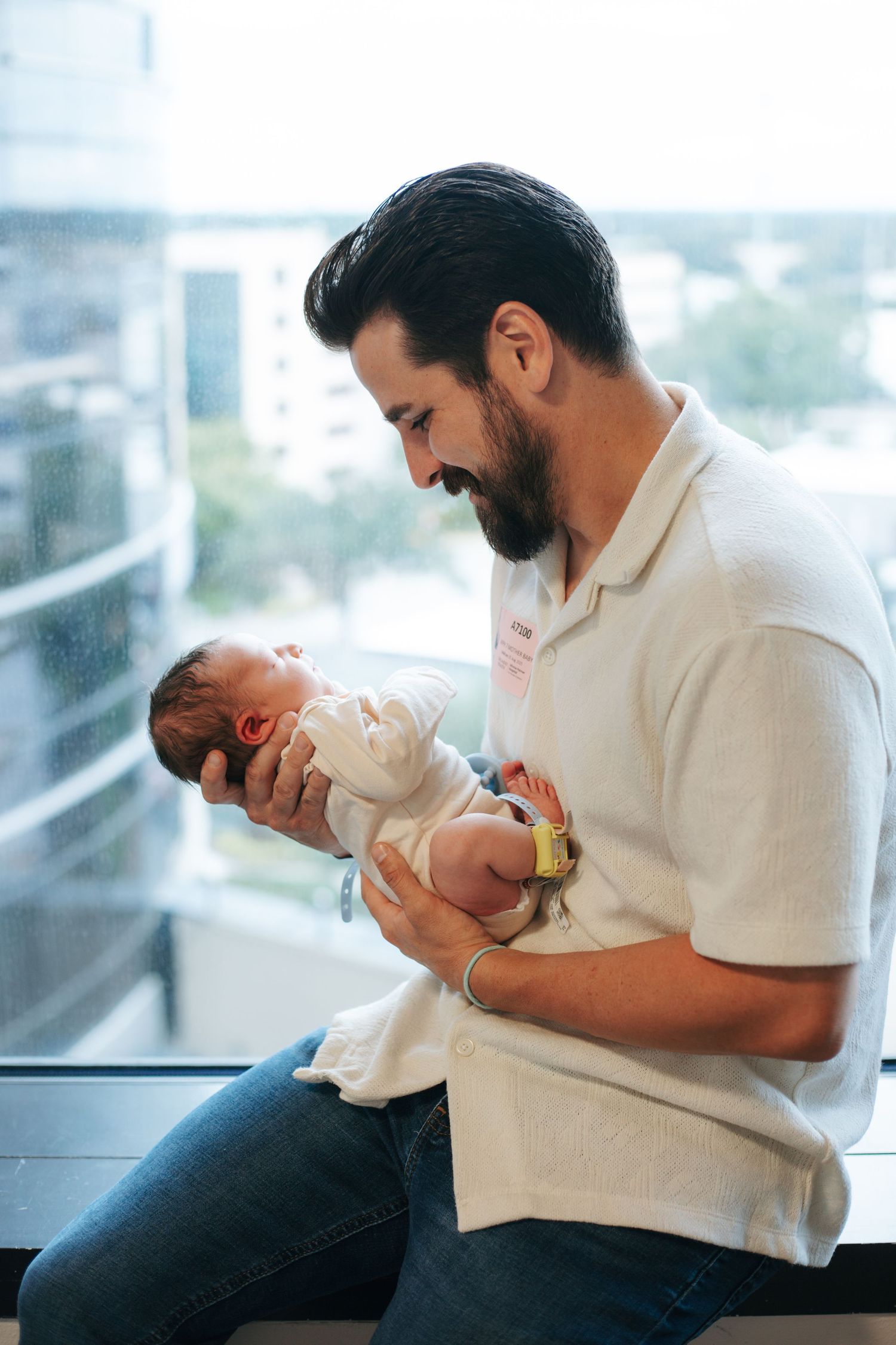 A series showing tender moments between parent and newborn by a bright window.