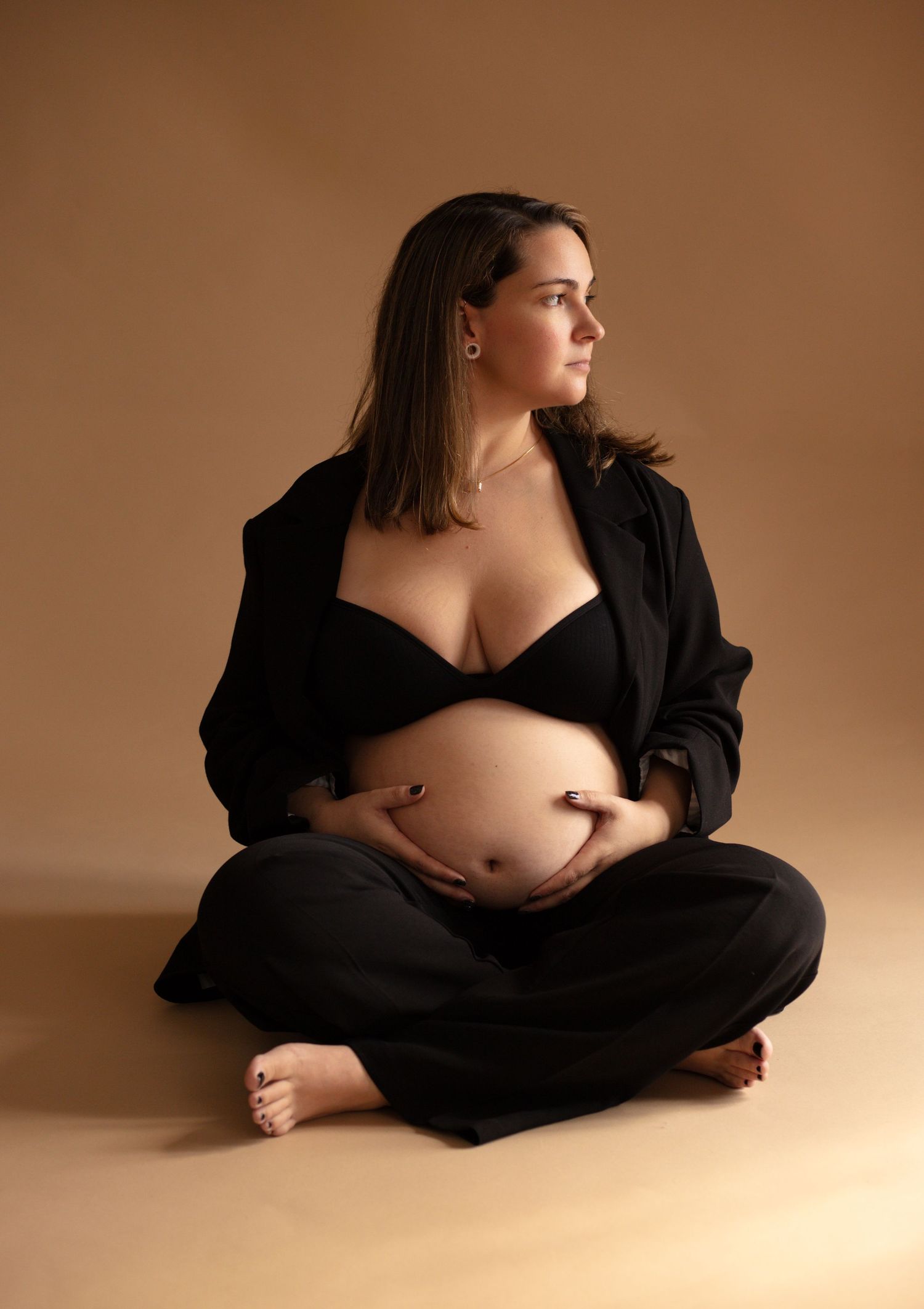 Artistic maternity portrait series showing silhouette in black wrap against warm brown backdrop in five elegant poses.