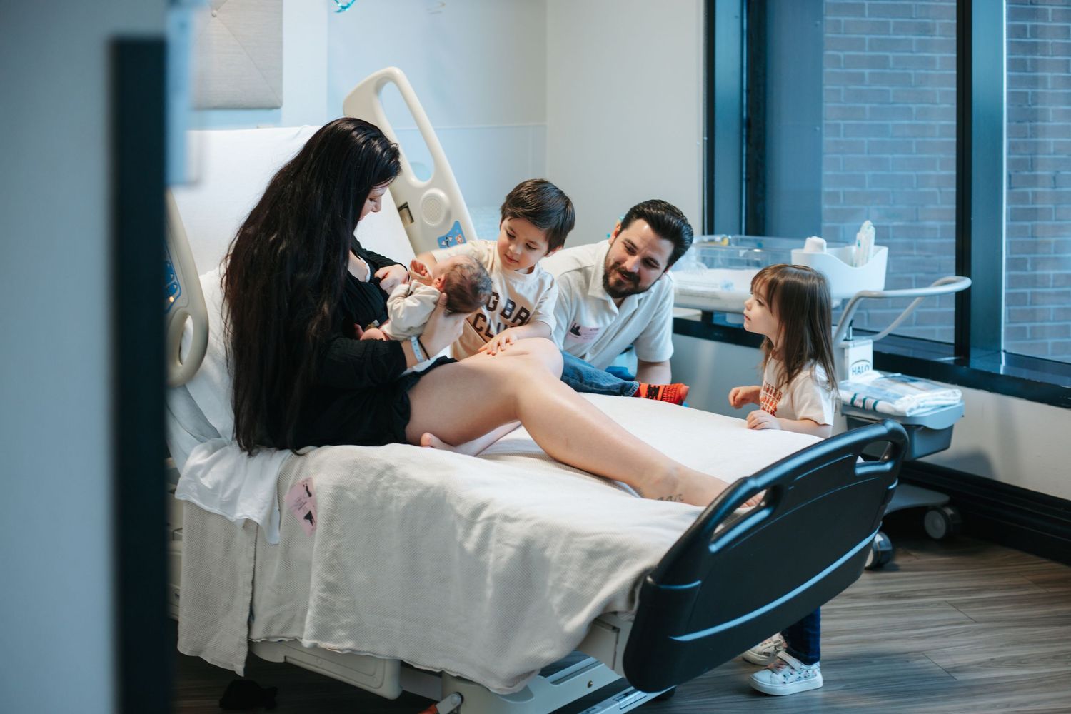Family gathered around hospital bed during birth celebration.