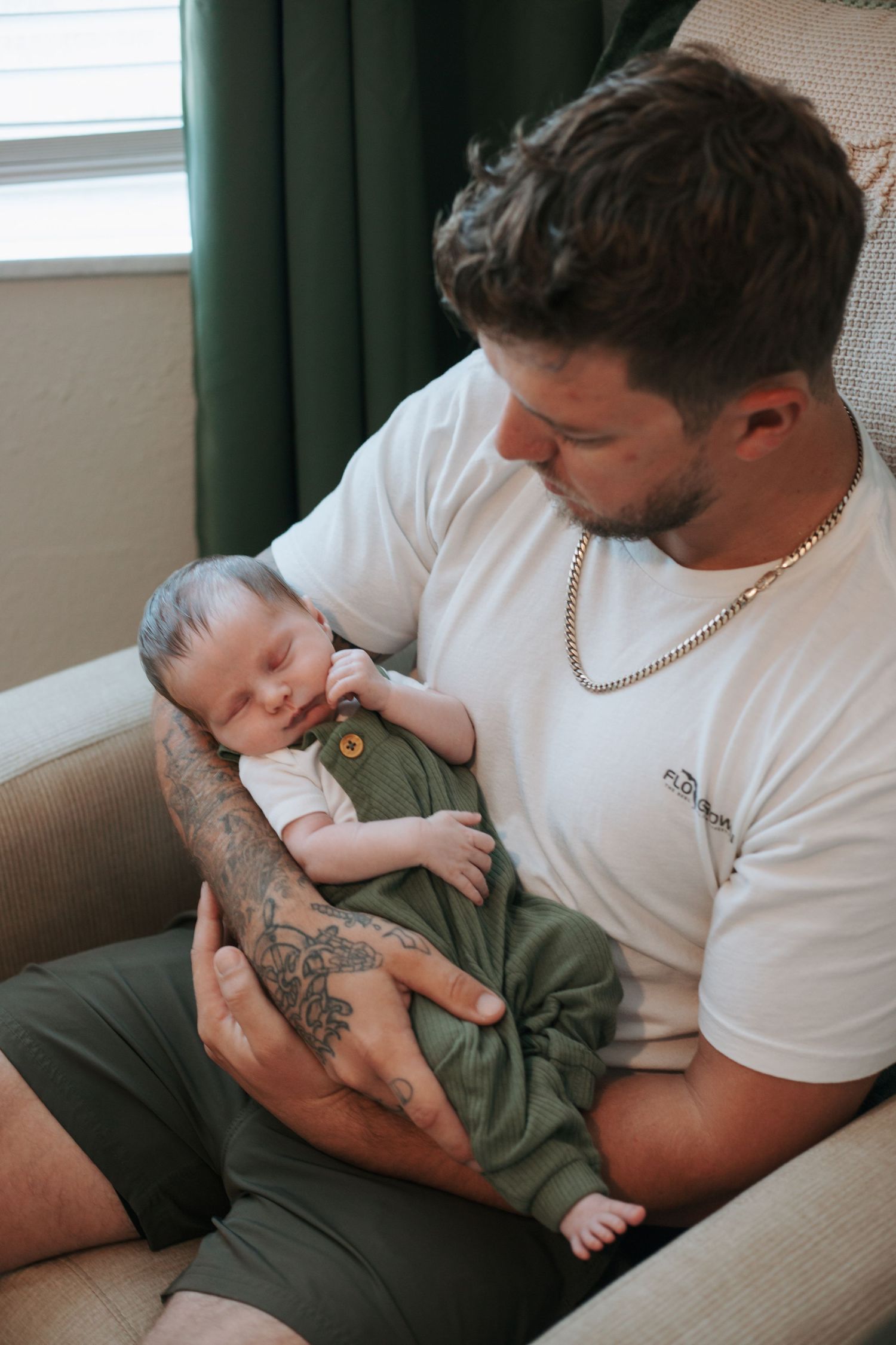 Intimate family moment on a couch with a baby wearing olive green clothing.