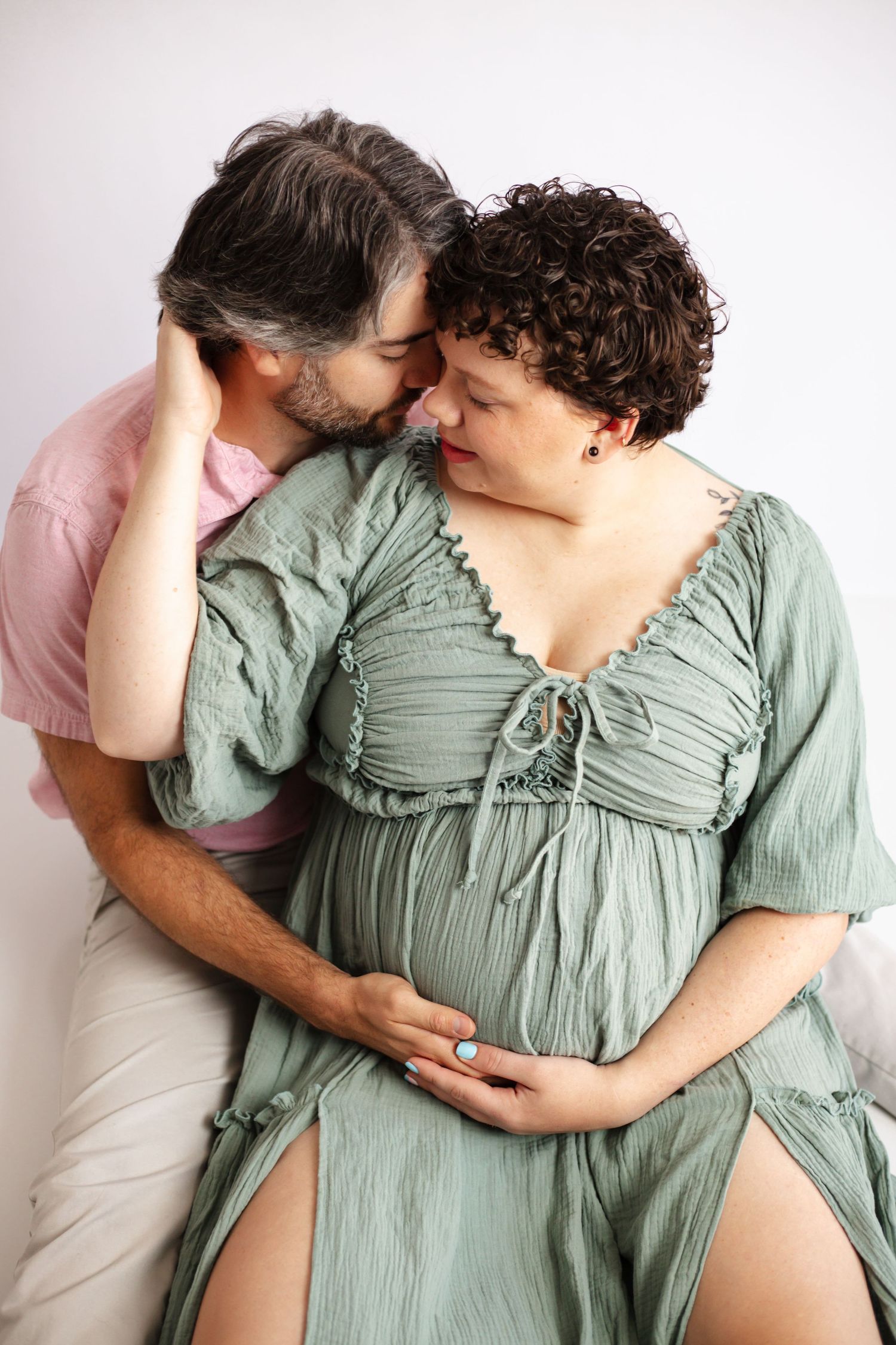 A couple in intimate poses wearing sage green and pink clothing shown in a series of three connected photos.